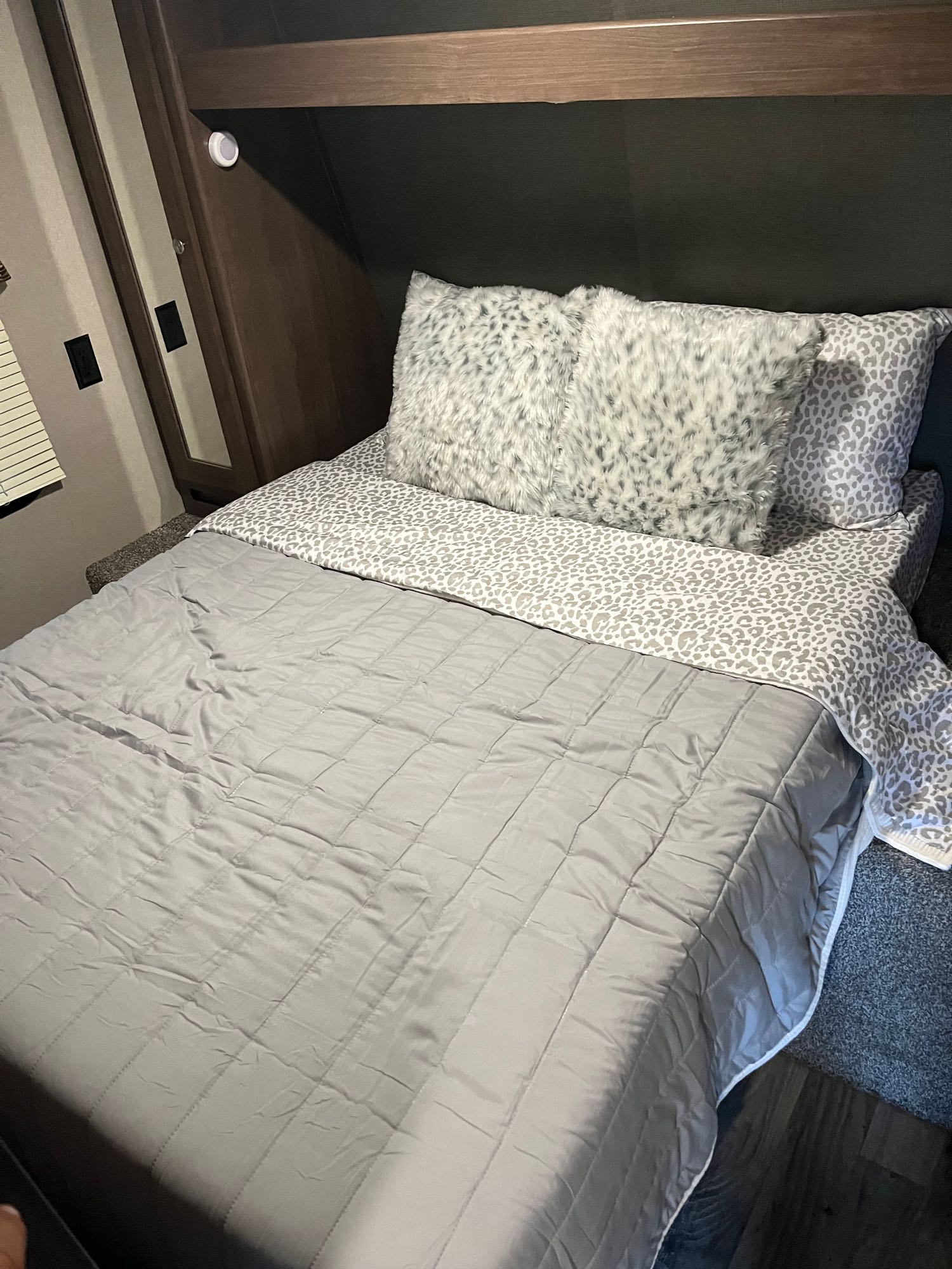 Cozy RV rental bedroom showcasing a grey quilted comforter, leopard print bedding, and fluffy pillows.. Keystone RV Hideout Luxury 2018