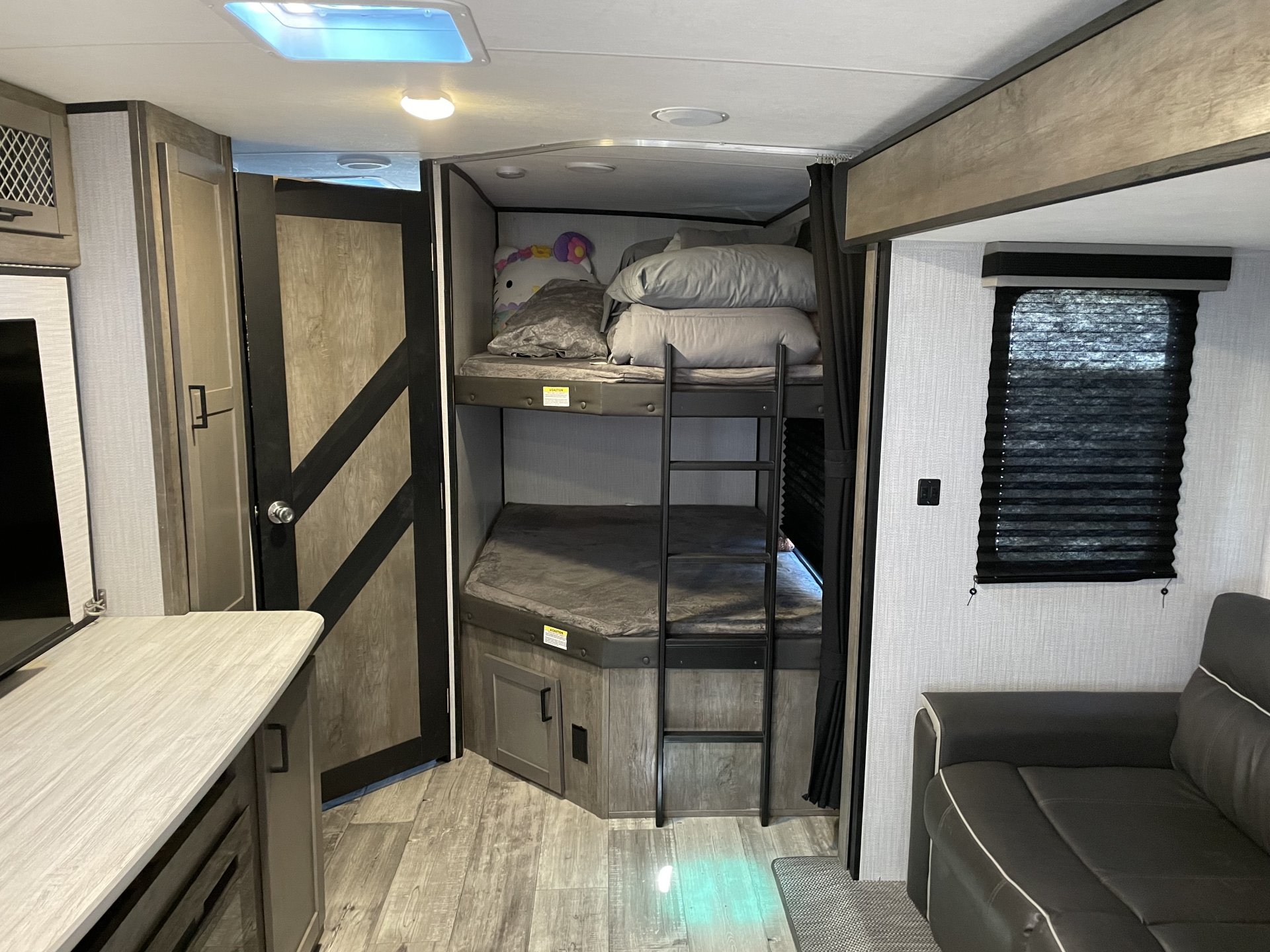 Cozy RV rental interior featuring a bunk bed setup with a ladder, a comfortable sofa, and wood-look flooring.. Heartland RVs North Trail 2021