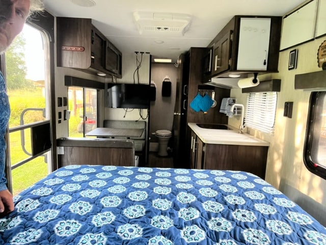 Inside a well-equipped RV rental: comfy bed in foreground, dinette, kitchen, and small bathroom visible for your travel comfort.. Forest River Cherokee Wolf Pup 2020