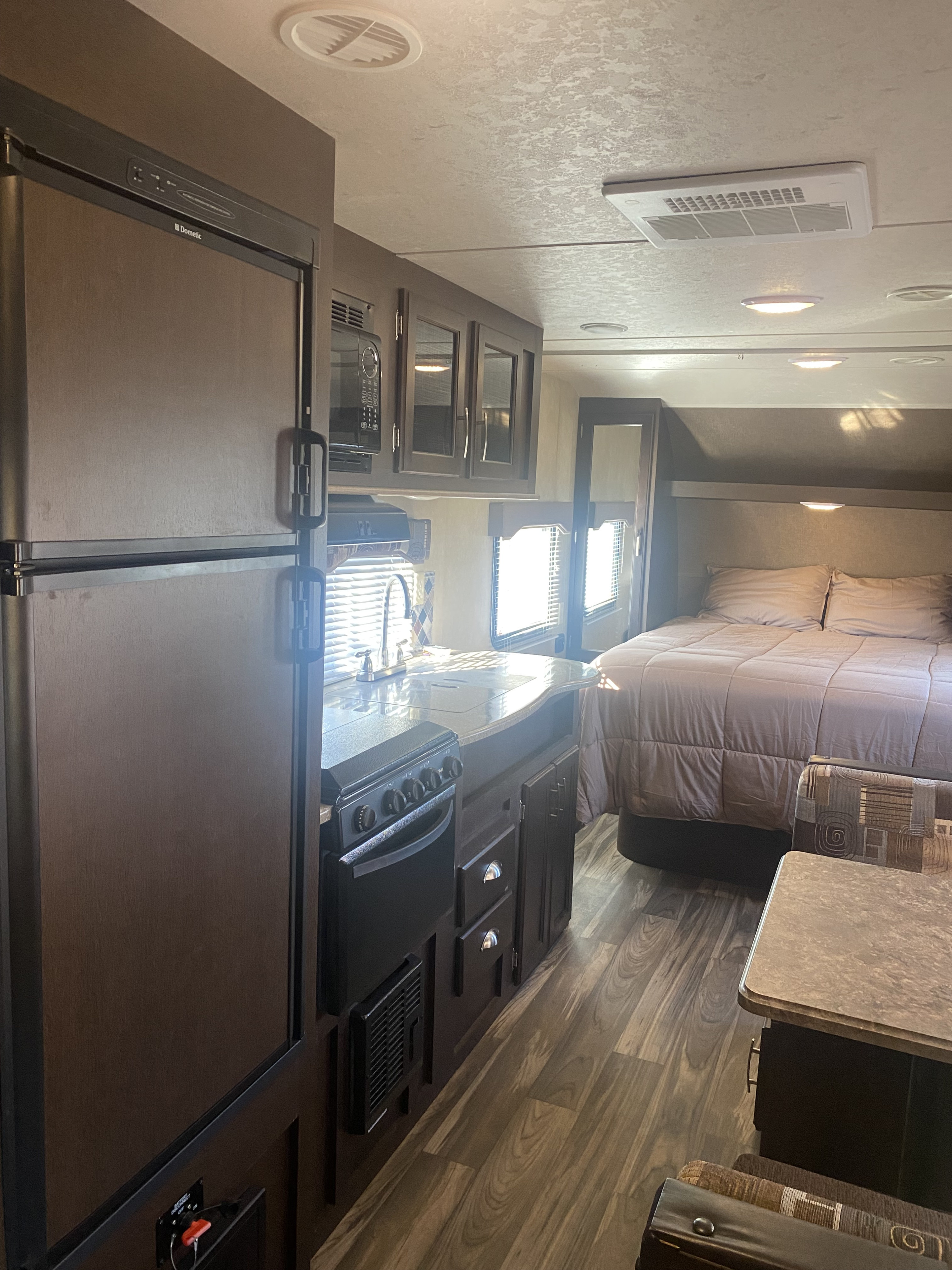 Cozy RV rental interior with a fully equipped kitchen, comfortable bedroom, and dining nook, ready for travel adventures.. Forest River Evo 2017