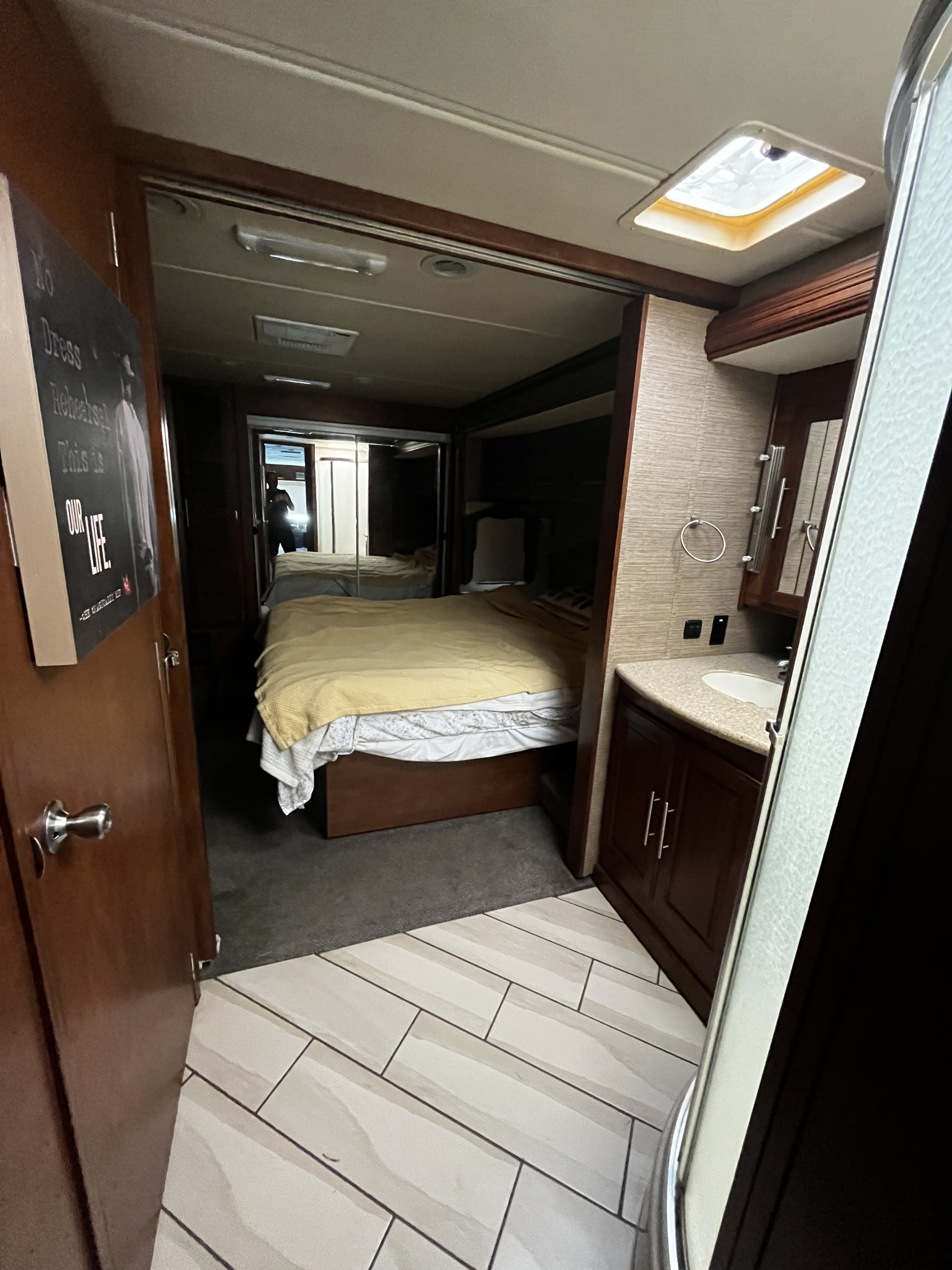 Spacious RV rental interior with a bedroom featuring a queen bed and mirrored closets, plus a modern bathroom with sink and shower.. Forest River Coachmen Pathfinder 2014