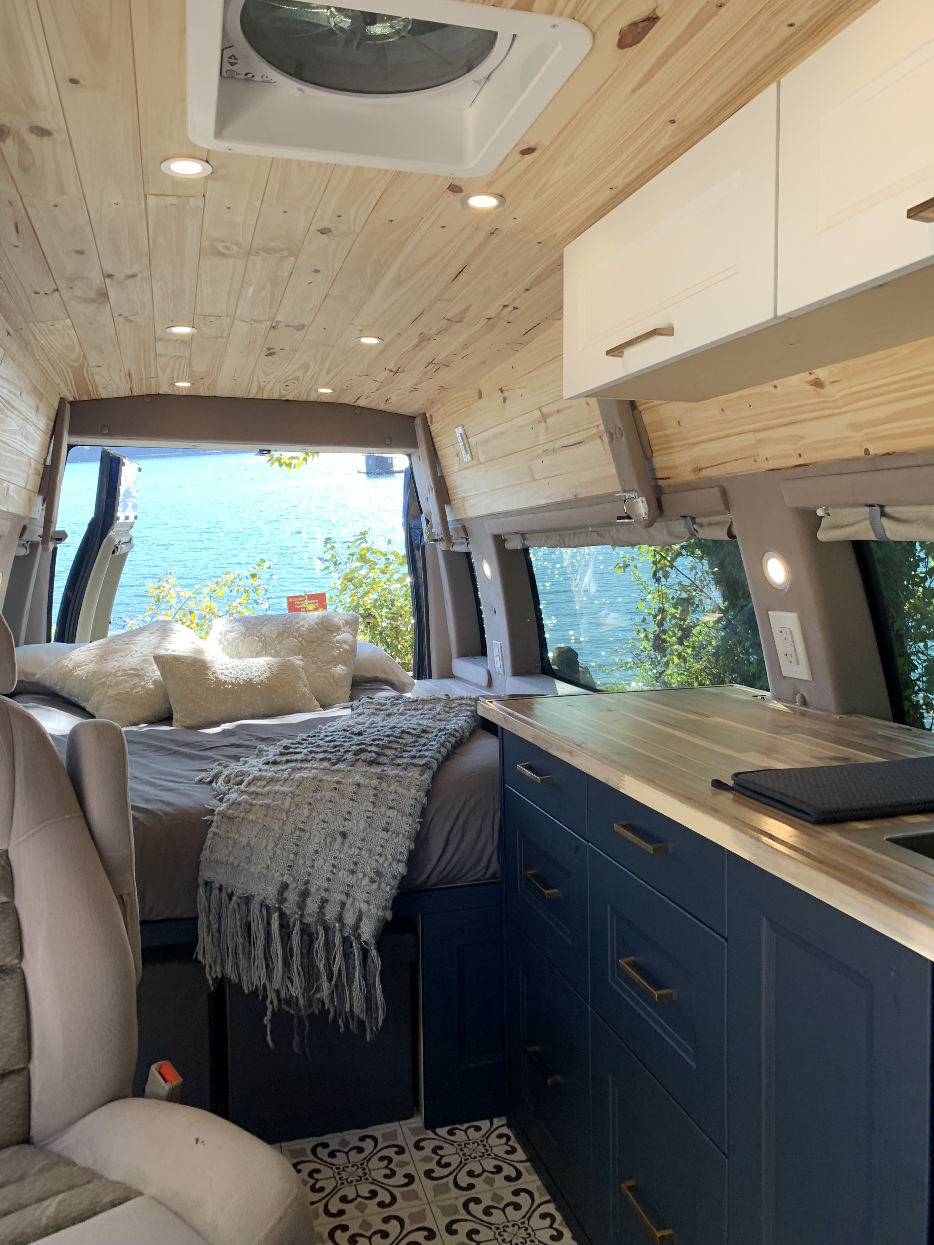 Experience van life in this stylish RV rental, featuring a cozy bed, modern kitchen, and stunning water views.. Ford Econoline 2013
