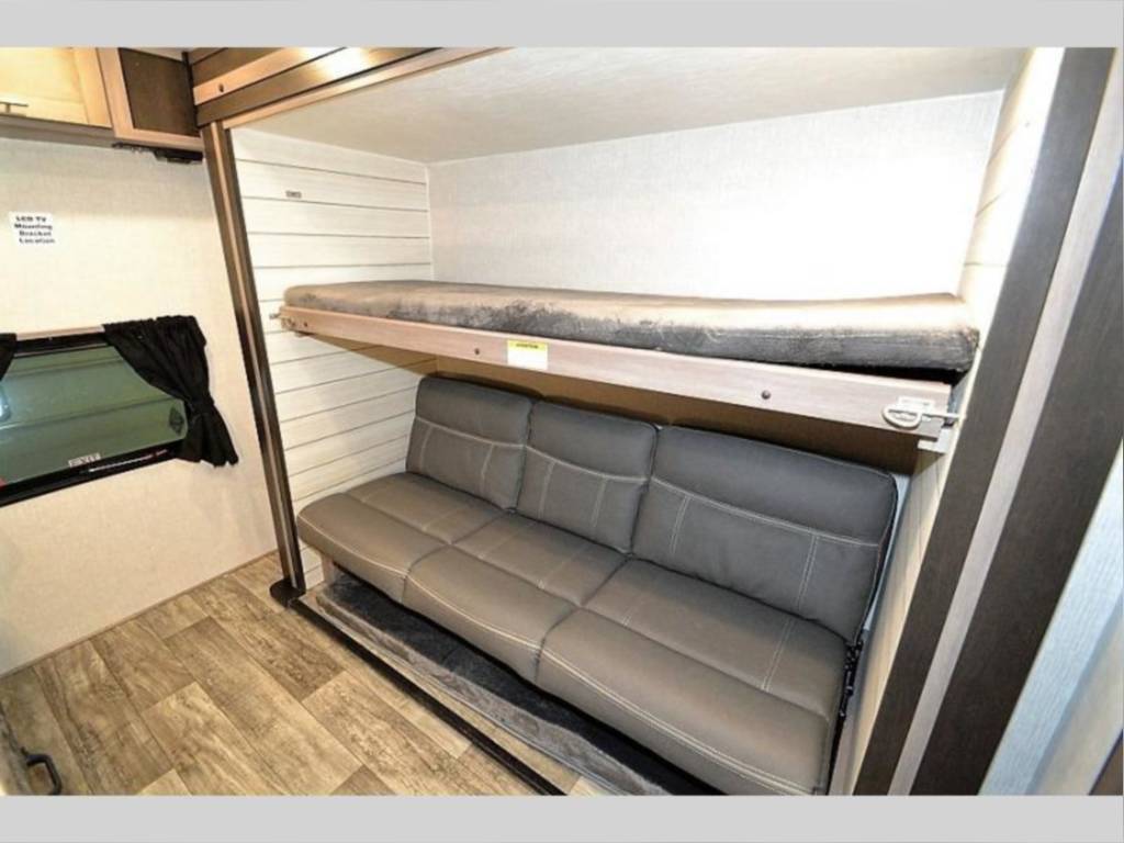 Versatile RV rental interior: a comfortable sofa transforms below a secure bunk bed, ideal for travel.. Crossroads RV Sunset Trail Super Lite 2021