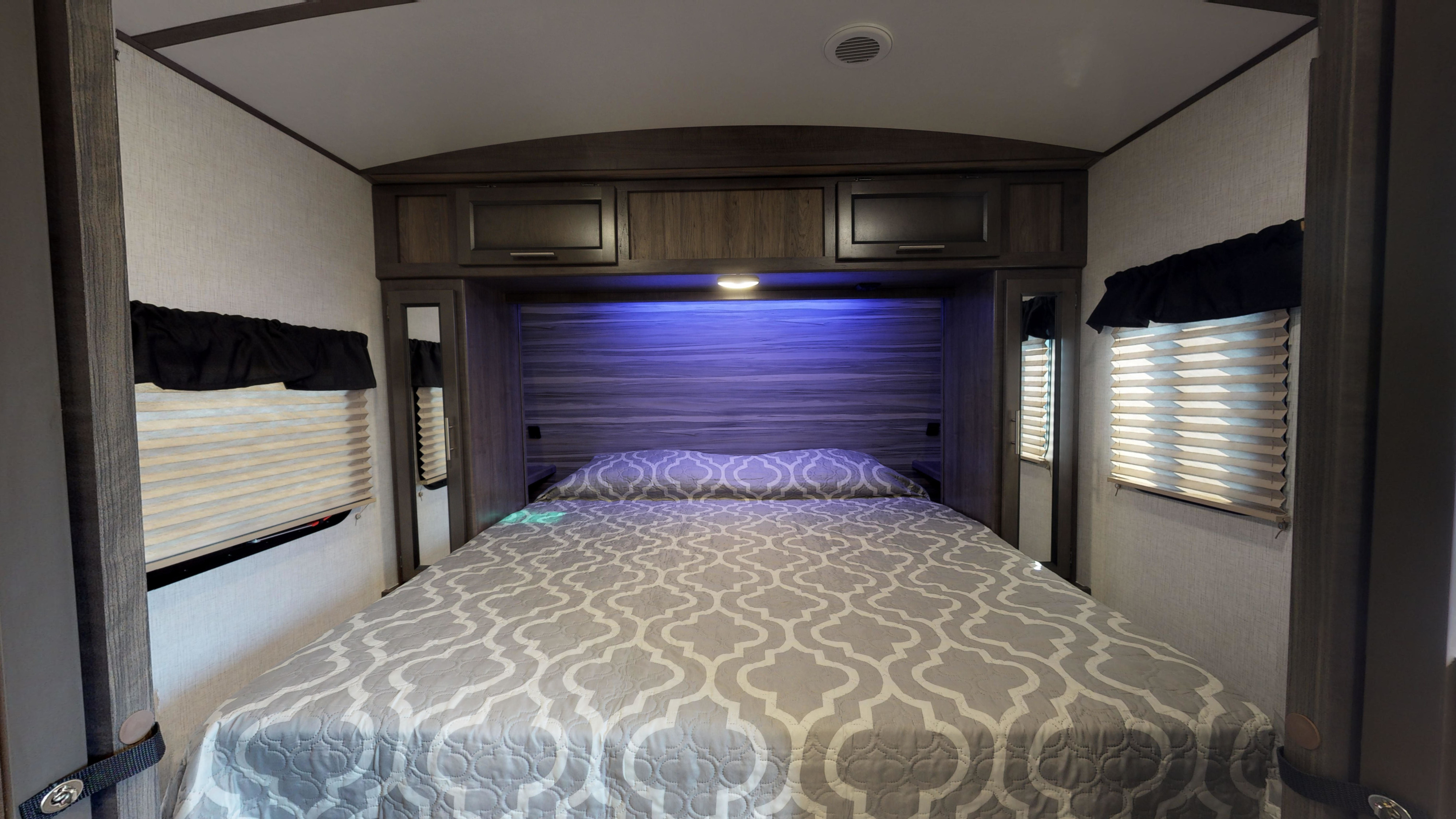 Cozy RV rental bedroom with a comfy bed, overhead storage, and ambient lighting. Perfect for travel trailer trips.. Crossroads RV Sunset Trail Super Lite 2021