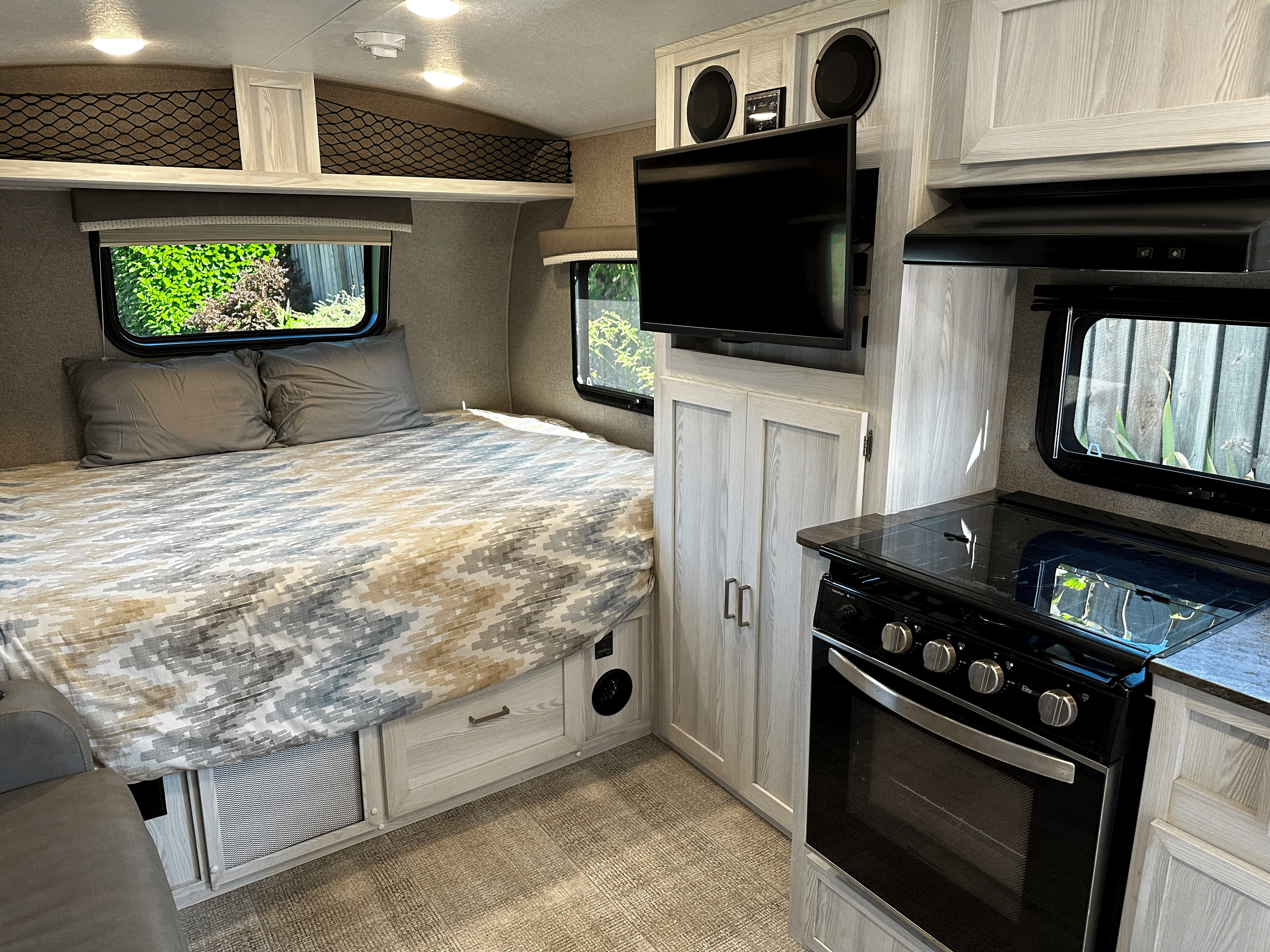 Explore this RV rental's cozy interior: bed, compact kitchen with oven/stove, TV, and smart storage solutions.. Forest River Rockwood Geo Pro 2020