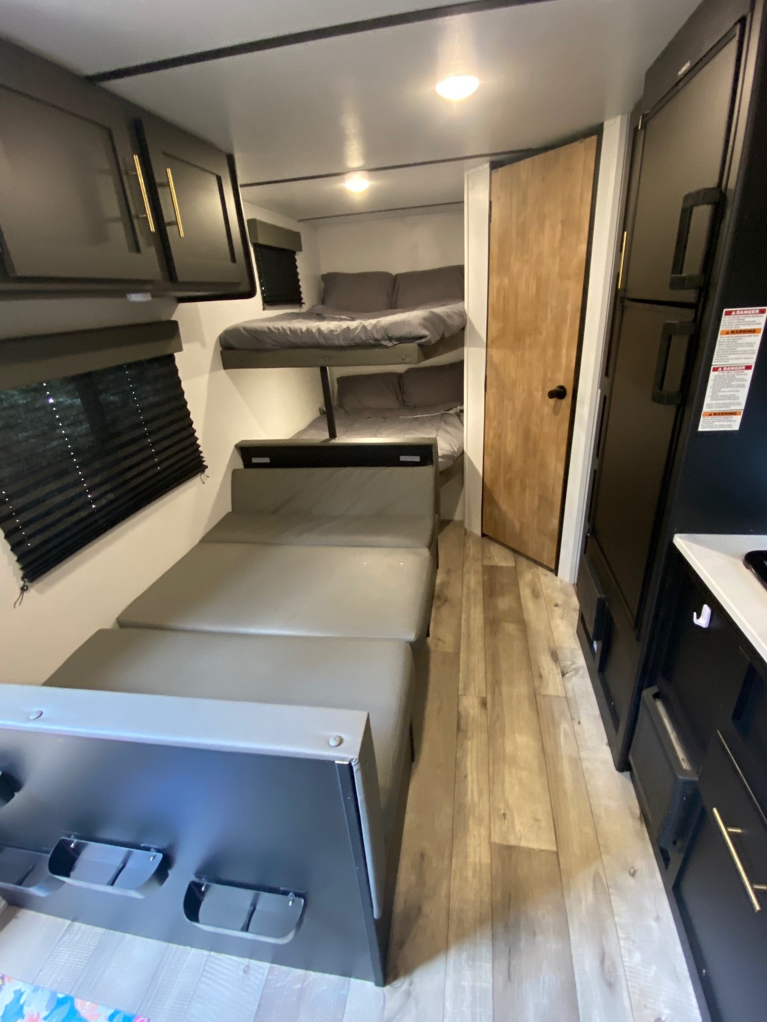 Inside an RV rental: comfy bunk beds, convertible seating, kitchen amenities, and stylish wood floors.. Keystone Springdale 2022
