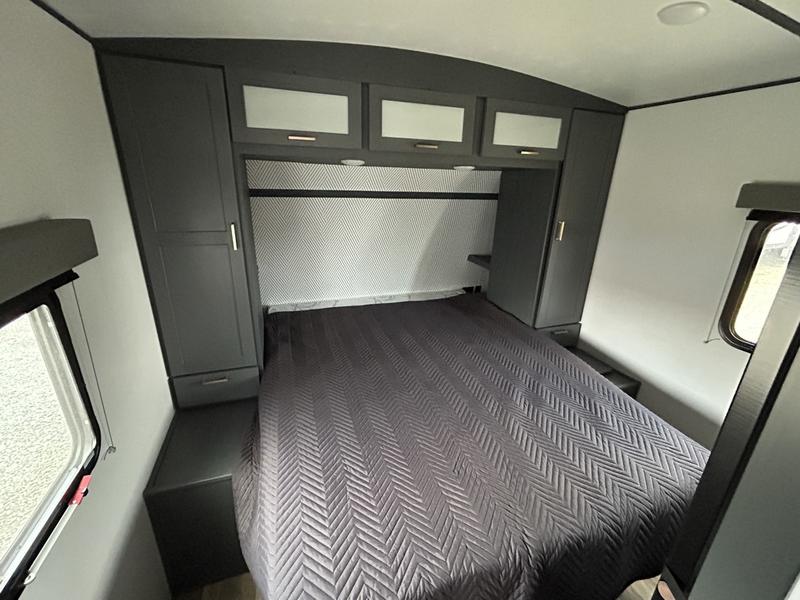 RV rental bedroom interior: spacious bed with overhead storage and side wardrobes in a modern grey design.. Keystone RV Bullet Ultra Lite 2023