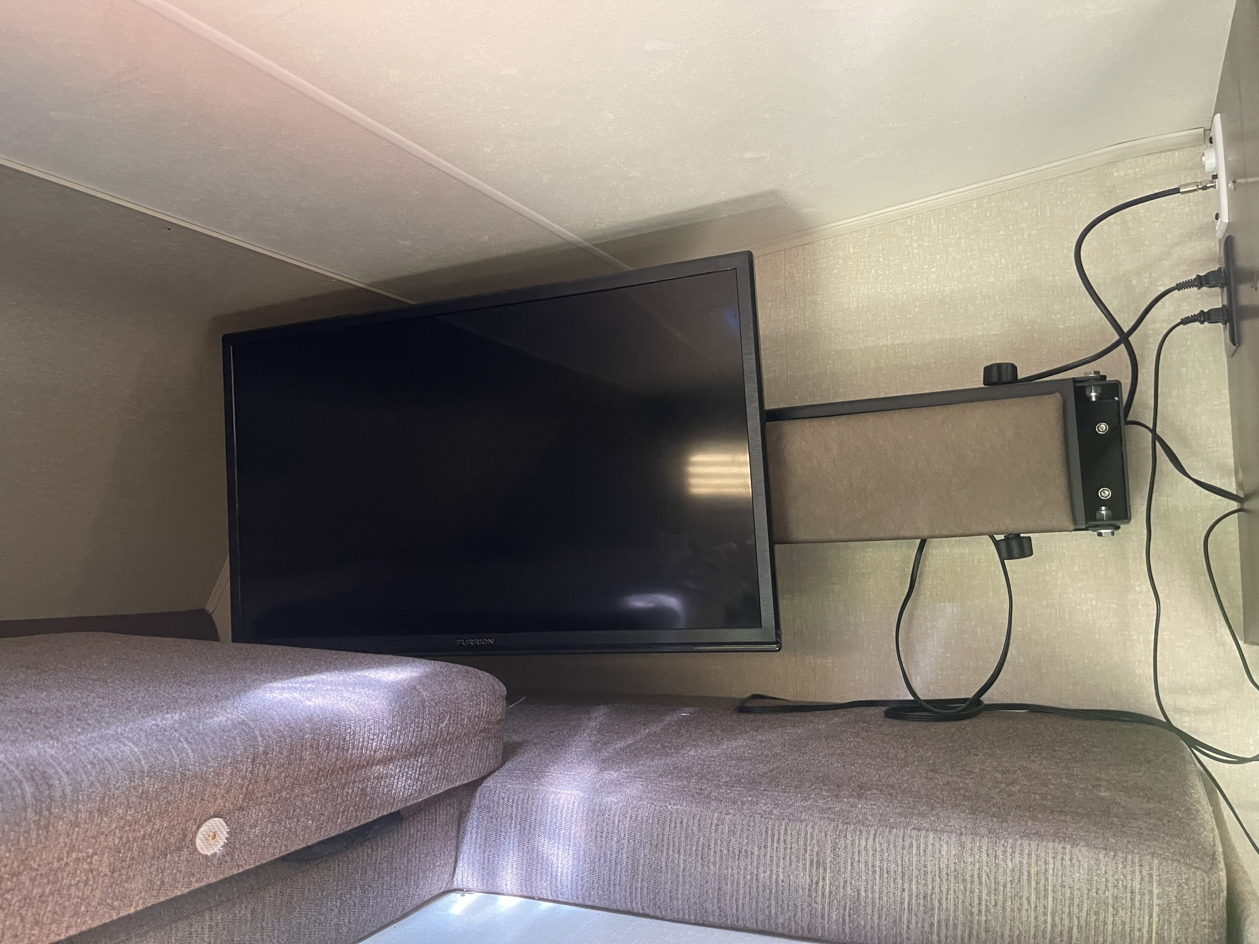 Inside an RV rental: a mounted Furrion TV above comfortable bunk seating, ideal for travel entertainment.. Ford Coachman 2018