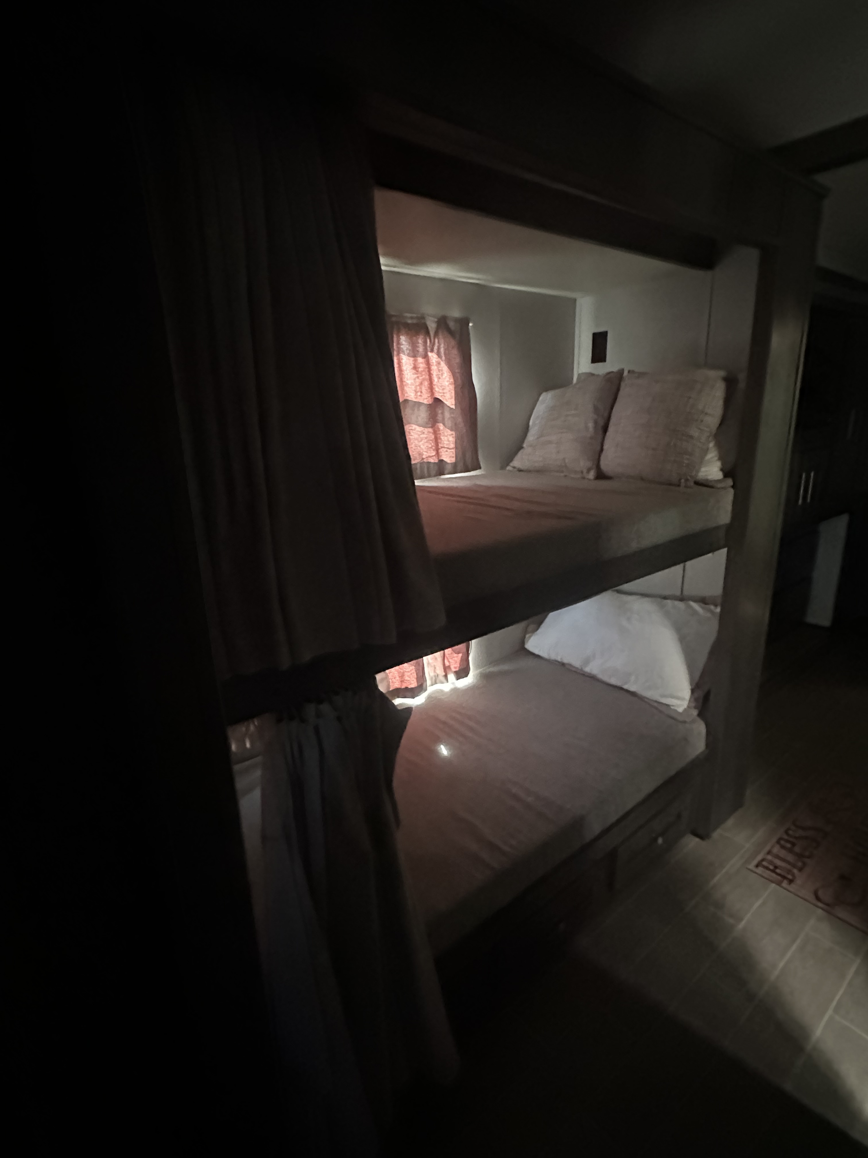 Dimly lit RV rental interior showing cozy bunk beds with light mattresses, patterned window curtains, and privacy drapes.. Georgetown GT5 2021