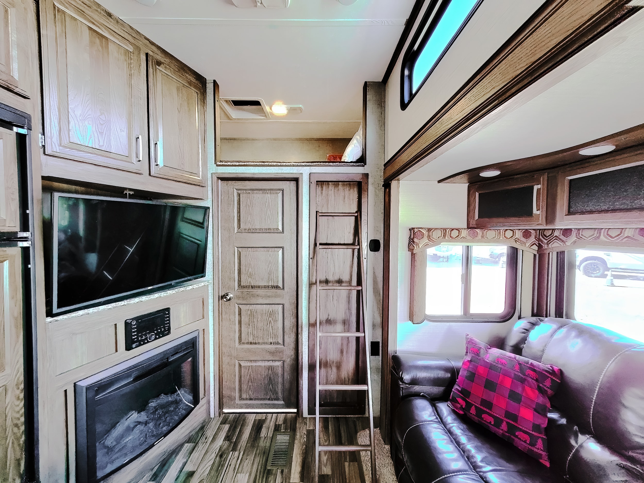 Cozy RV rental interior with a comfy sofa, TV, fireplace, and ladder to a bunk. Perfect for family adventures.. Keystone Cougar 2017