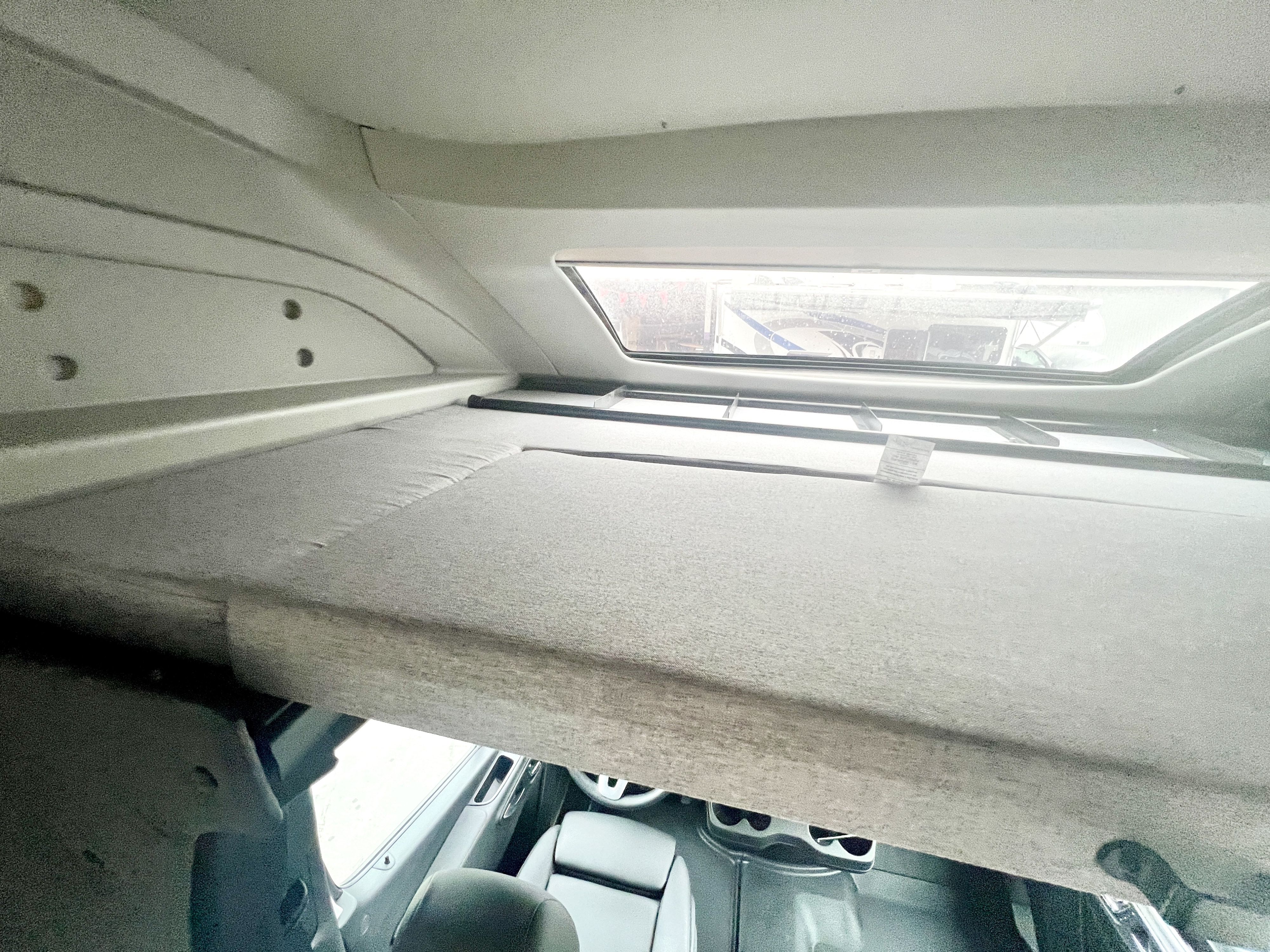 Overhead sleeping bunk in an RV rental, offering comfortable space above the driver's cabin with a skylight view.. Coachmen Prism 2024