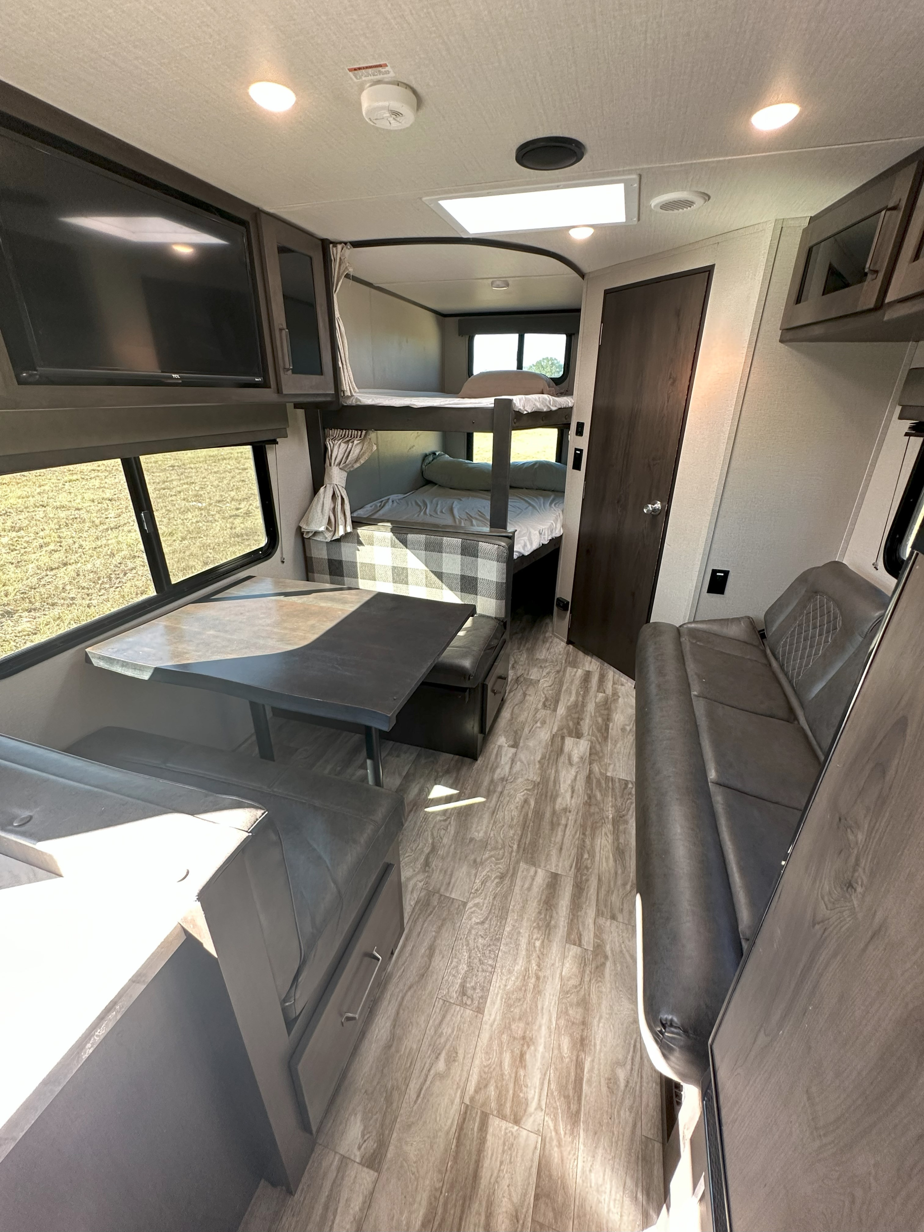 Cozy RV rental interior: bunk beds, dinette booth, and sofa offer comfort. Ideal for family travel adventures.. Grand Design Transcend Xplor 2022