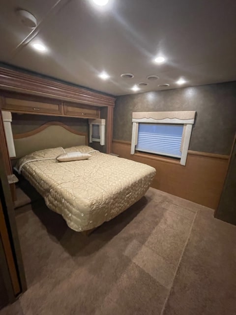 Spacious RV rental bedroom with a cozy bed, overhead cabinets, soft lighting, and window, ideal for comfortable travel.. Bay Star Bay Star Motorhome 2014