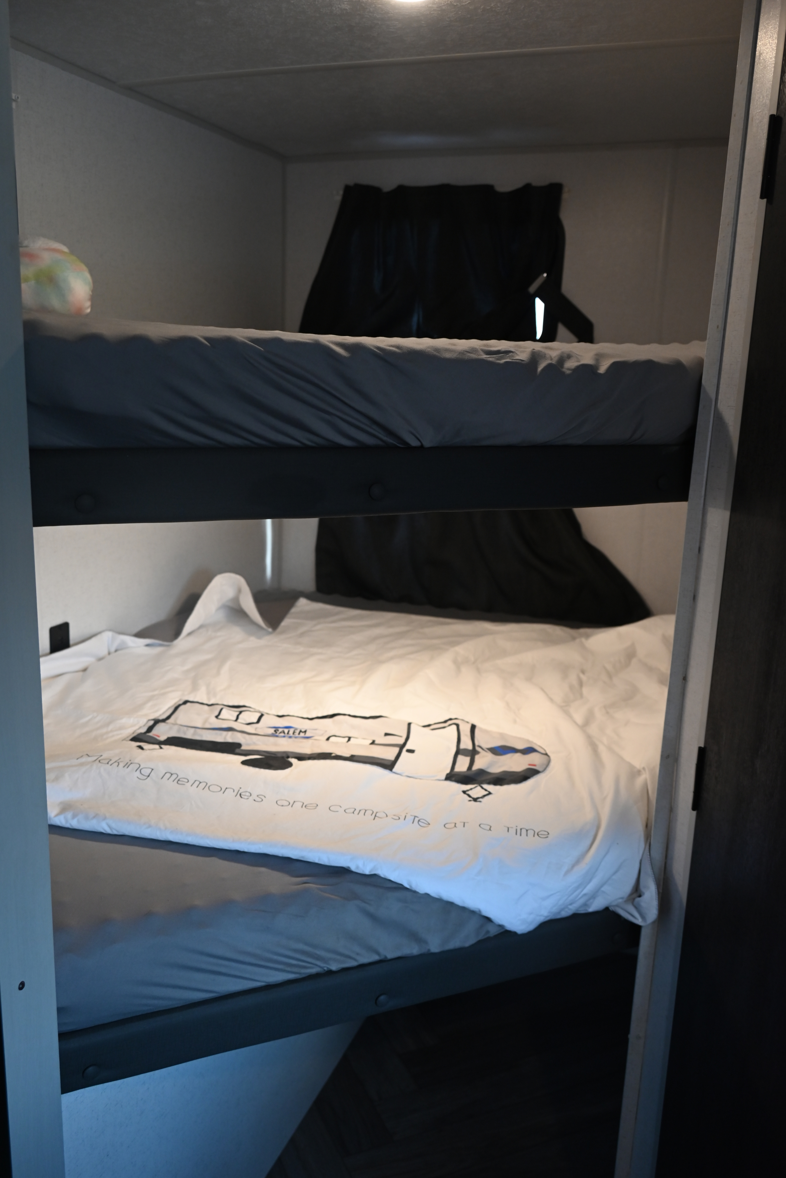 Cozy bunk beds in an RV rental, featuring a "Salem" RV themed duvet on the lower bunk, perfect for camping memories.. Forest River Salem FSX 2022