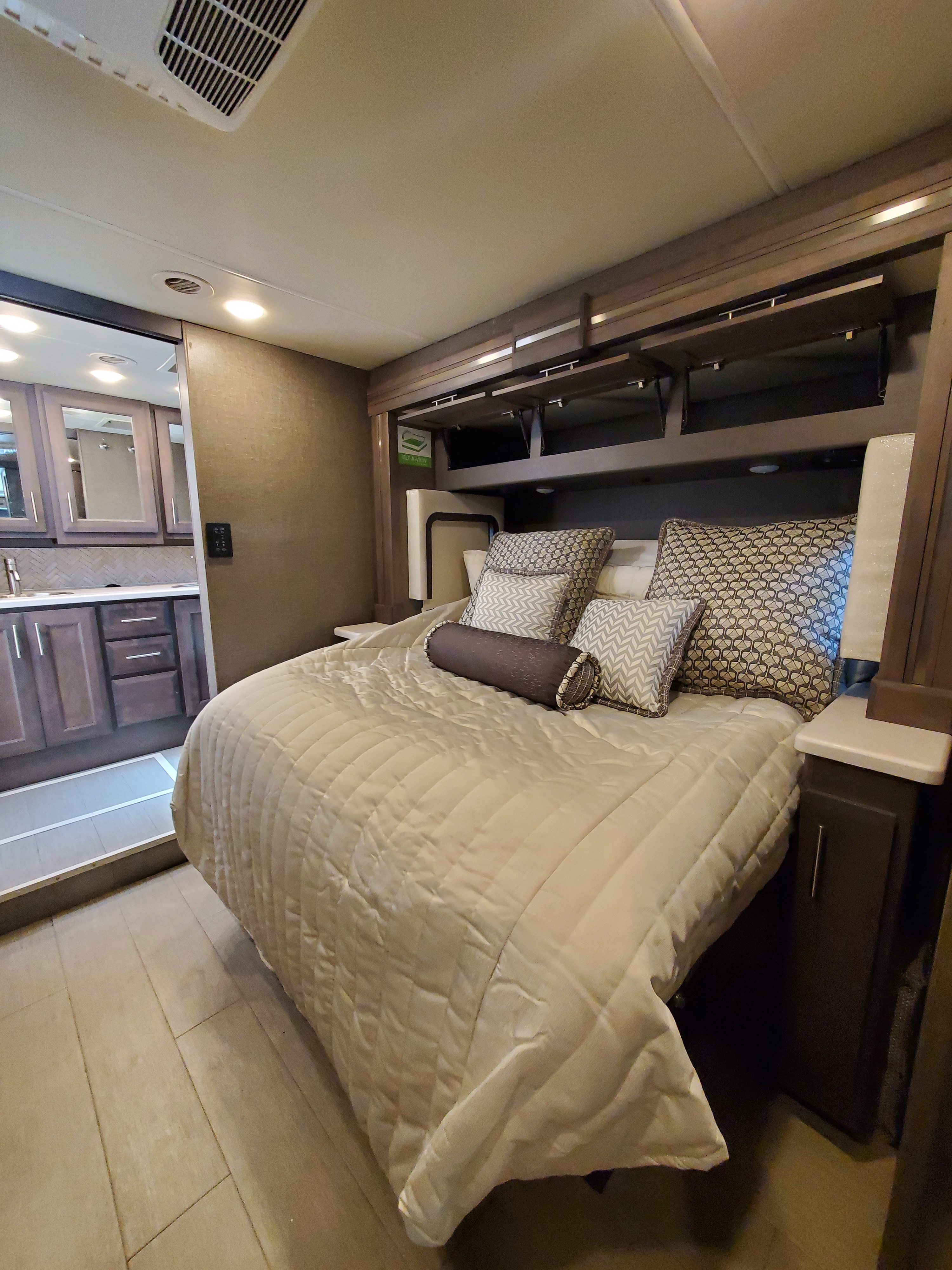 Comfortable RV rental bedroom with bed, overhead storage, and a sliding door leading to a modern bathroom.. Thor Palazzo 2022