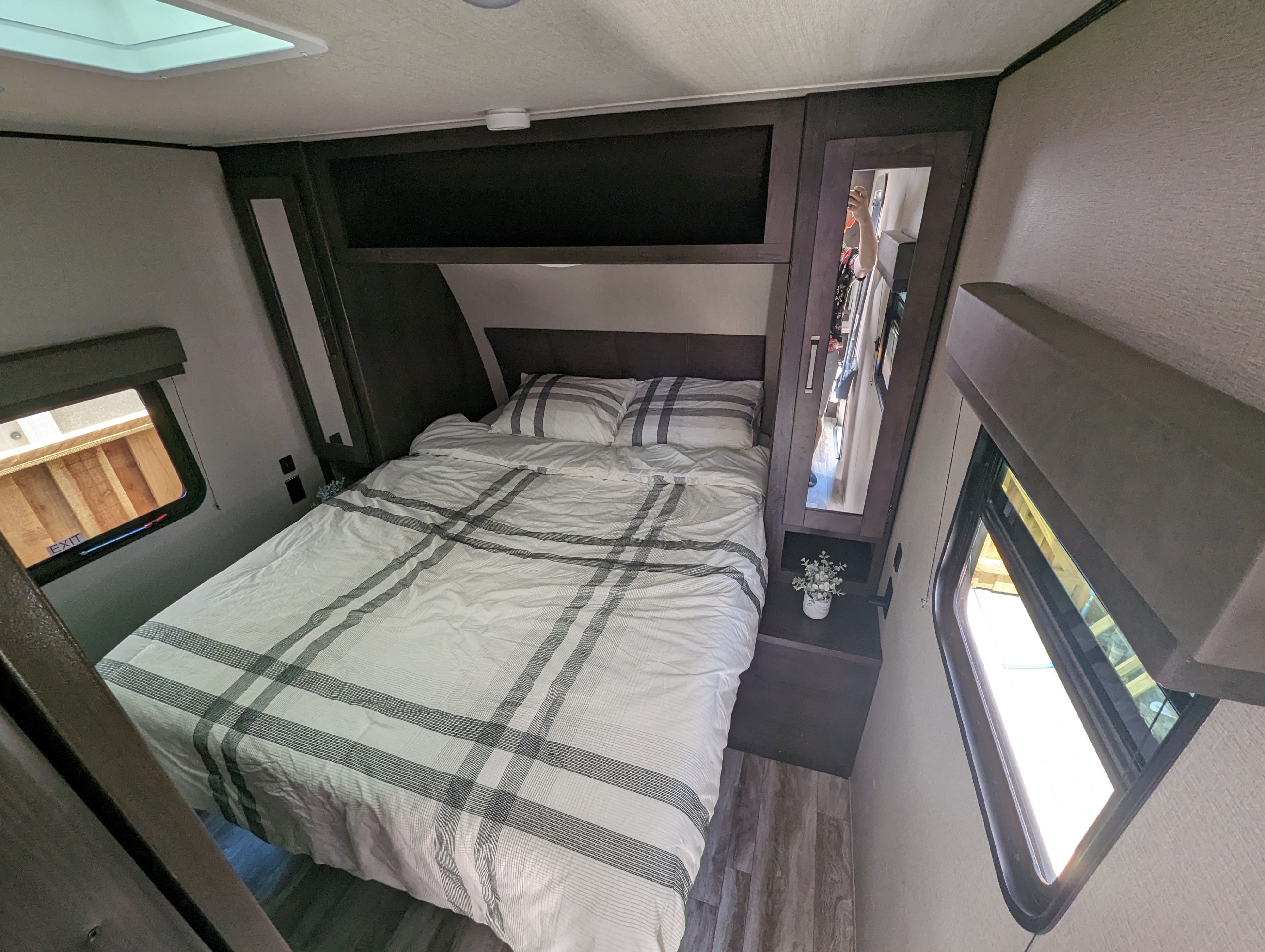 This RV rental bedroom offers a comfortable queen bed, ample storage, and windows, ready for relaxing journeys.. Grand Design Transcend Xplor 2022
