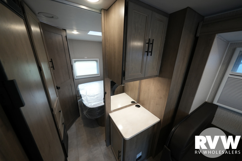 Interior of an RV rental showing a small bathroom, galley counter with storage, and a glimpse of the bedroom.. Coachmen Prism 2024