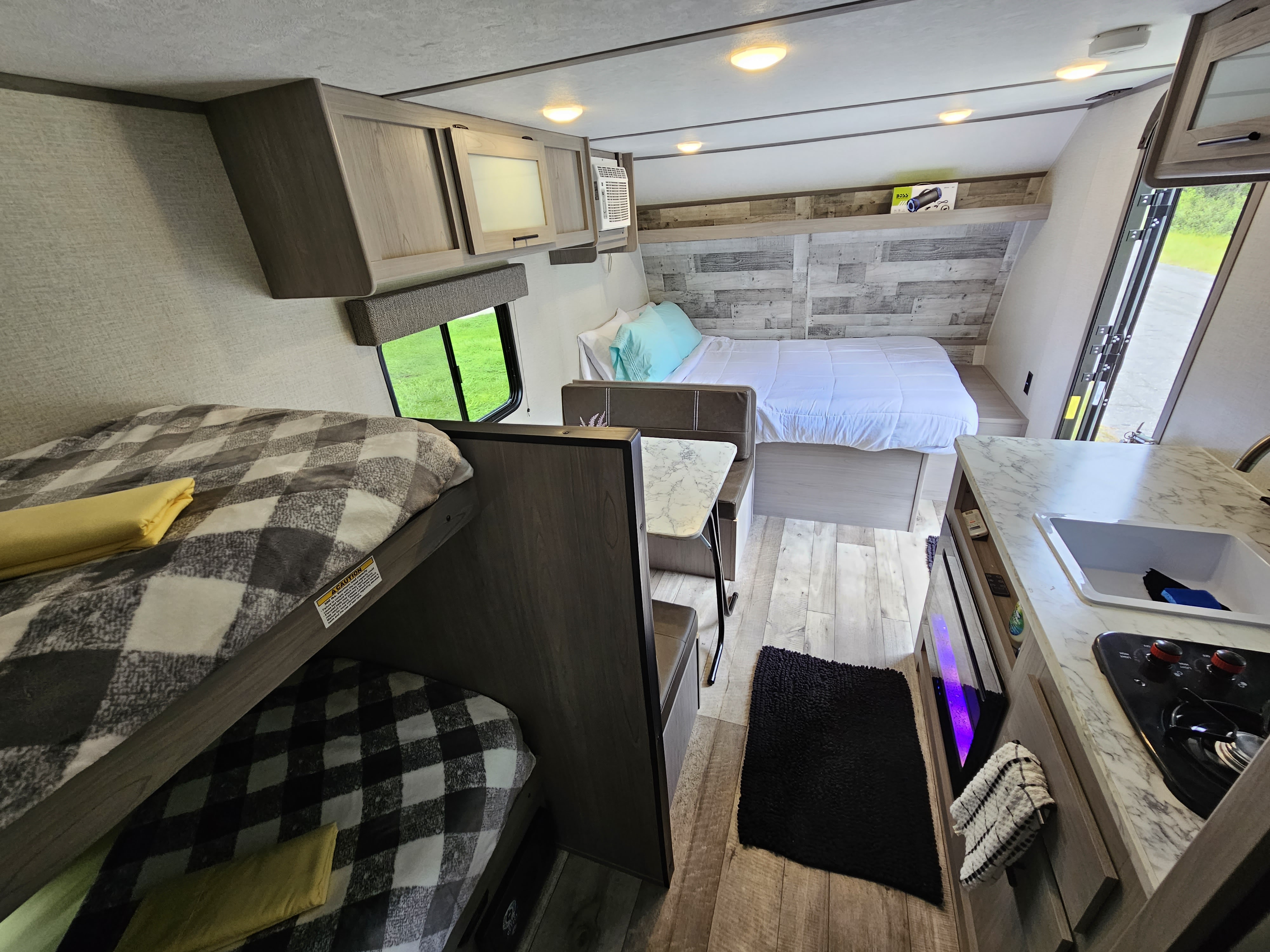 RV rental interior: A cozy space with bunk beds, a main bed, dining area, and a functional kitchen.. Coleman Lantern 2023