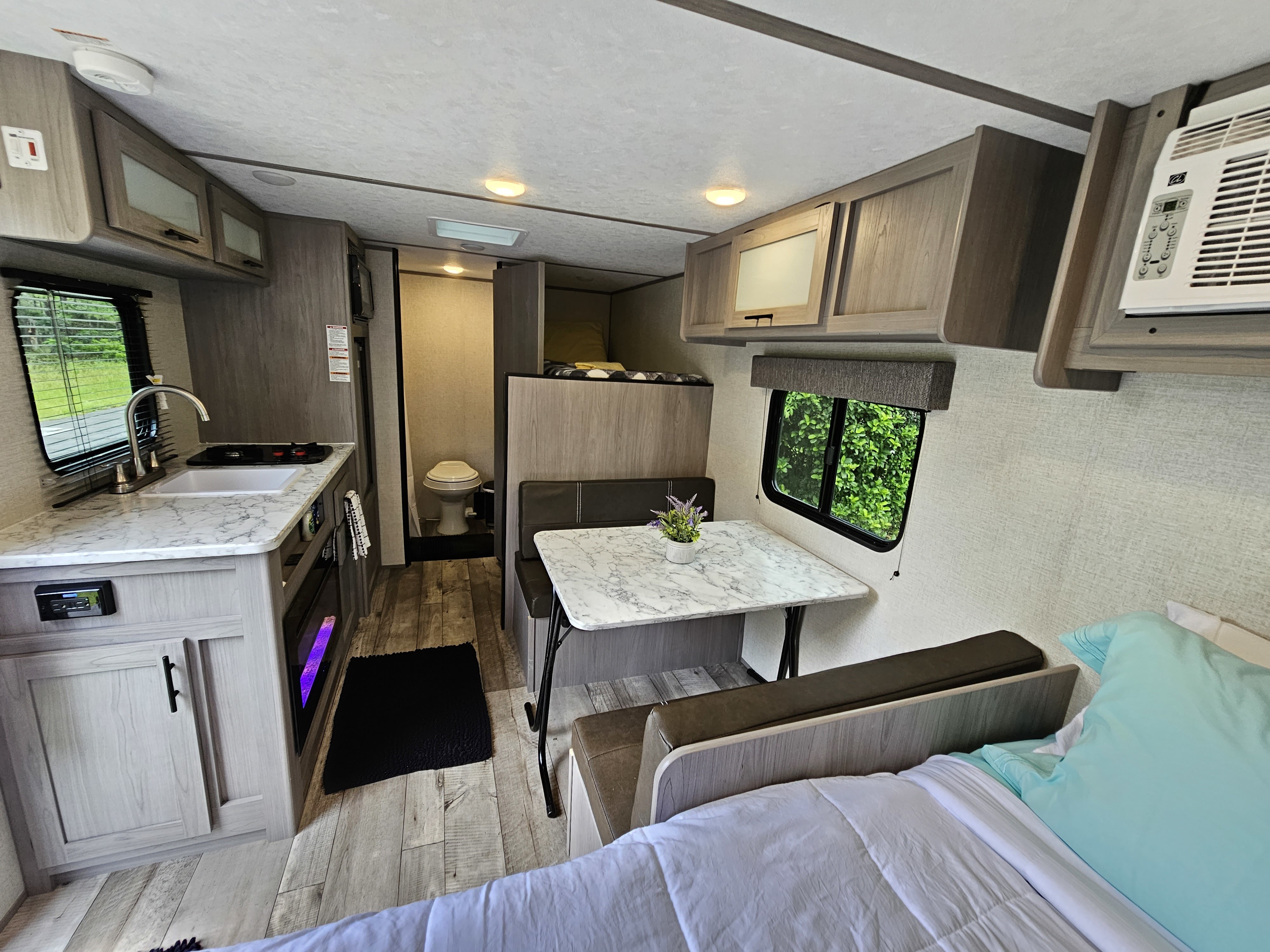 Spacious and modern RV rental interior featuring a full kitchen, dining area, bed, bunks, and bathroom. Perfect for travel.. Coleman Lantern 2023