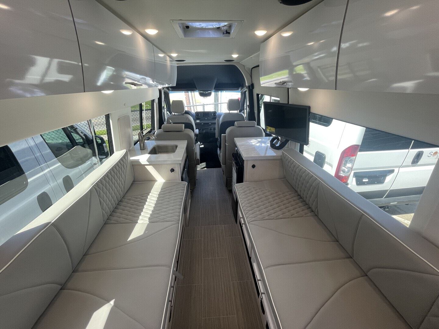 Step inside this RV rental! Modern interior with twin long bench seats, a kitchen sink area, and a mounted TV. Bright & spacious.. CLASS B 2022