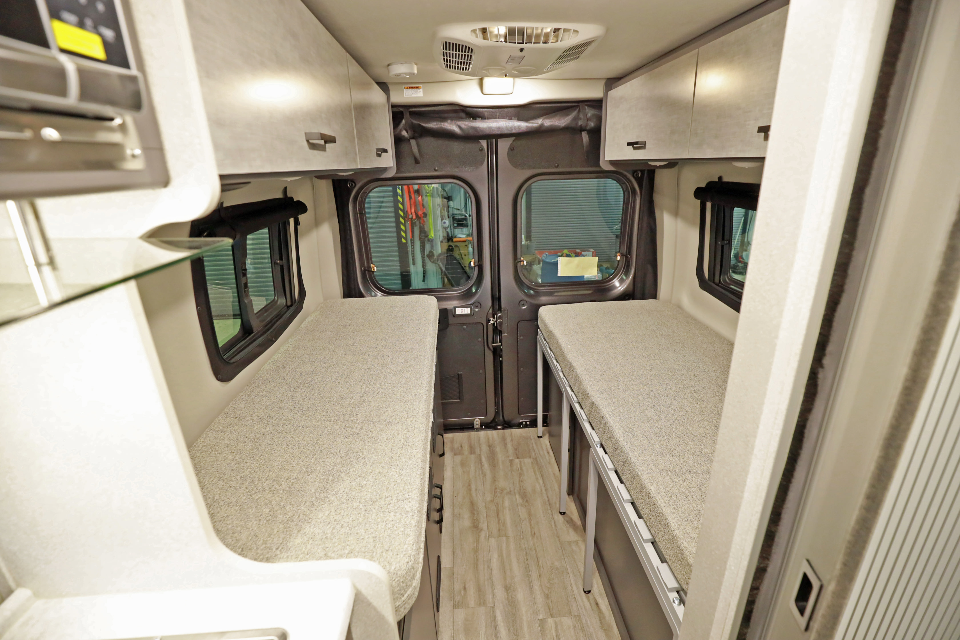 RV rental: Inside a camper van showing two comfortable narrow beds, overhead storage, and rear doors, perfect for mobile lodging.. Thor Motor Coach twist 2022