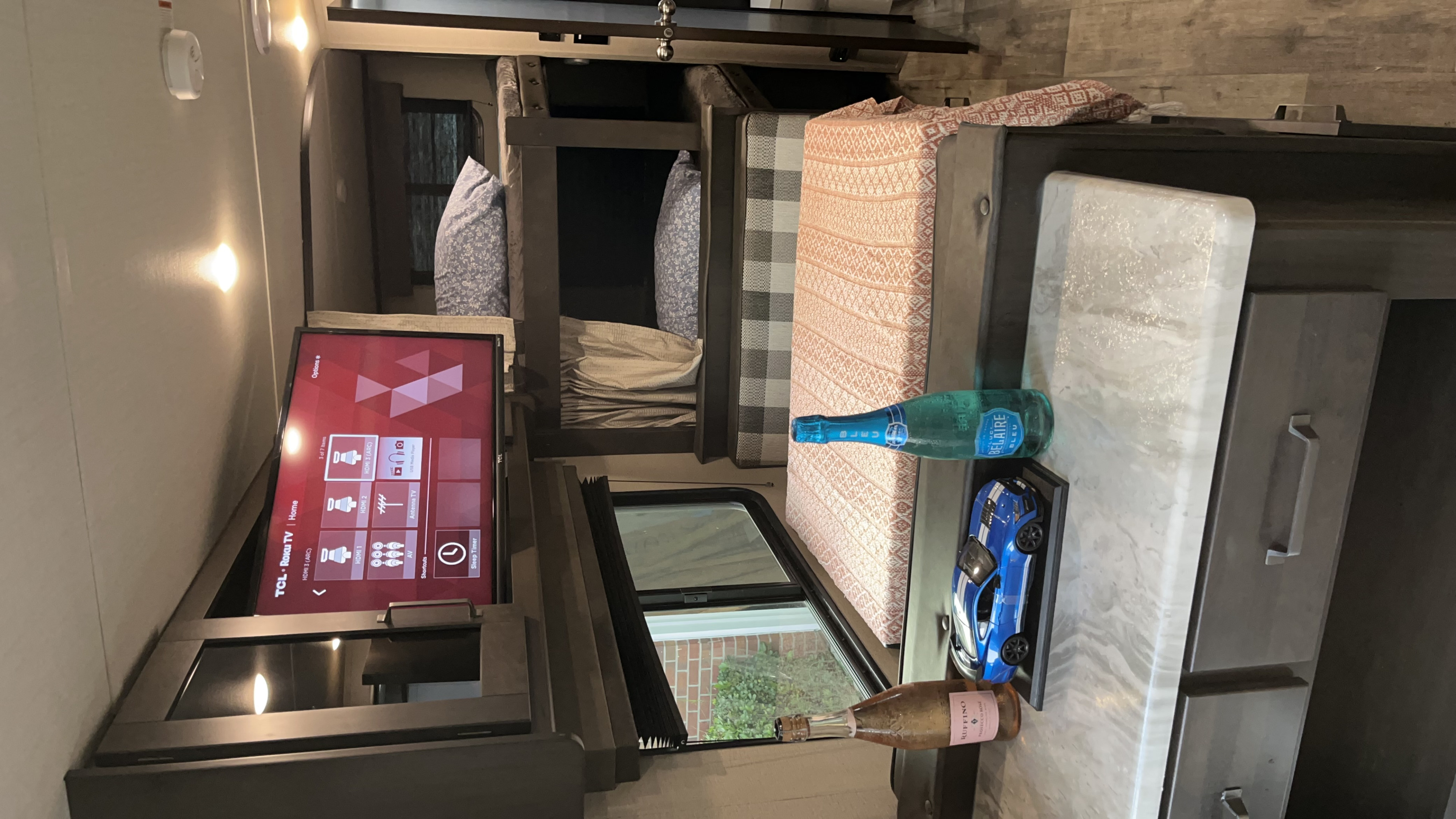 Cozy RV rental interior with TCL Roku TV, bunk beds, and a counter. Perfect setup for travel and road trips.. Grand Design Transcend Xplor 2022
