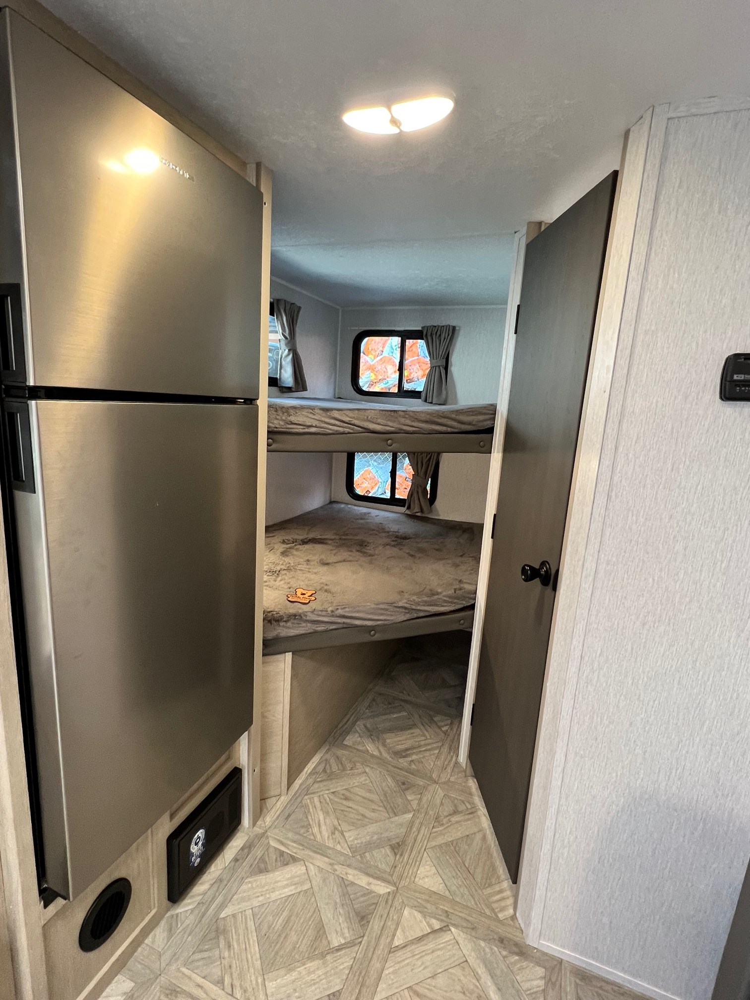 RV rental interior featuring a stainless steel fridge, two bunk beds with windows, and light patterned flooring.. Forest River Salem Cruise Lite 2024