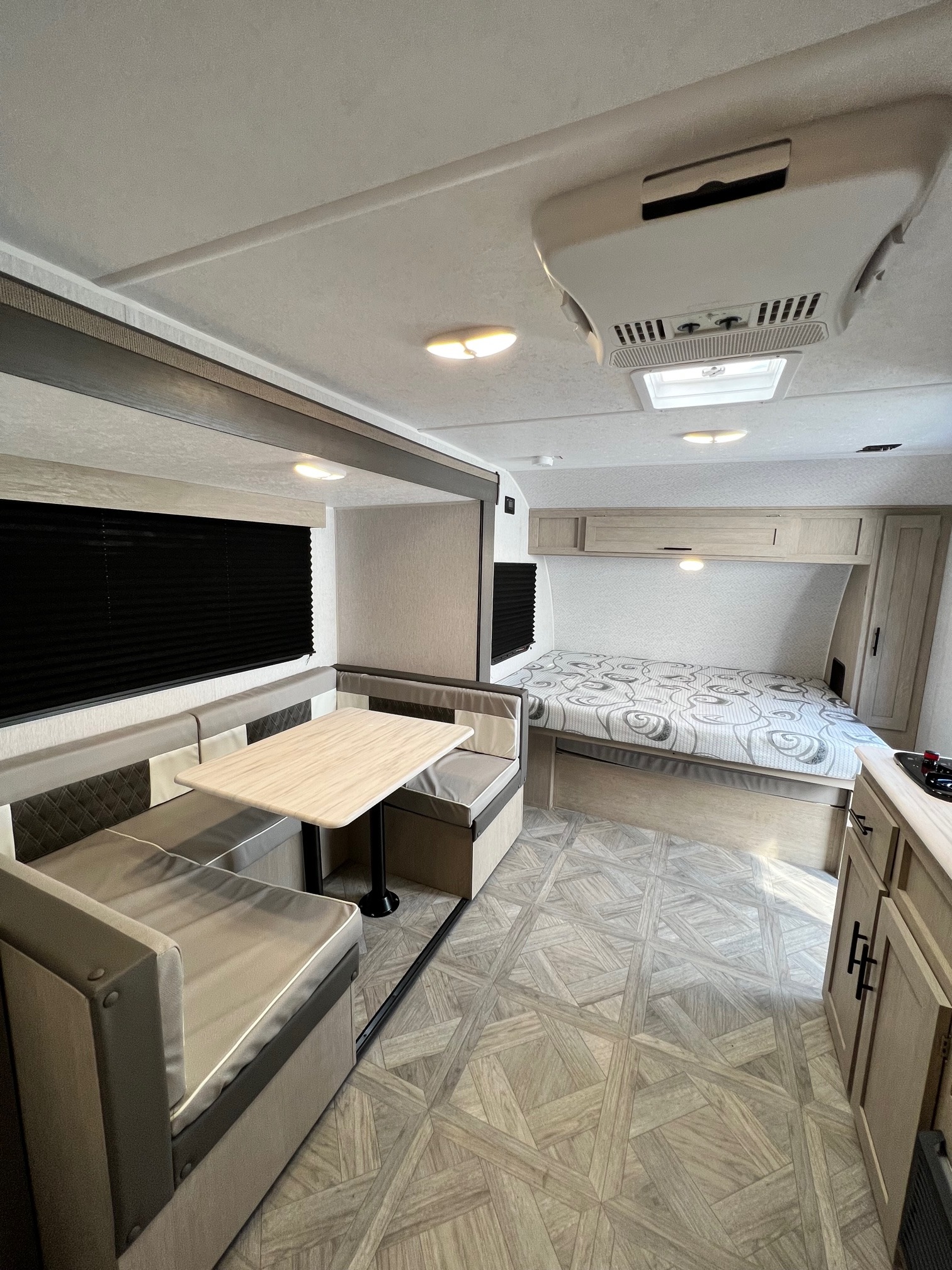 A bright and clean rv rental interior showing a comfortable dinette, a bed, and a compact kitchen area.. Forest River Salem Cruise Lite 2024
