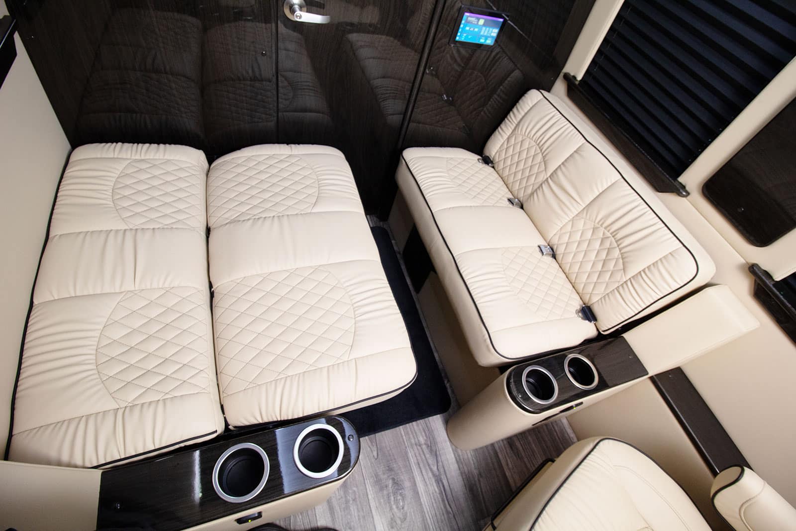 Custom RV rental interior featuring plush cream quilted seating that converts to a bed, wood accents, and integrated cup holders.. Ultimate Toys Ultimate Cruiser 2024