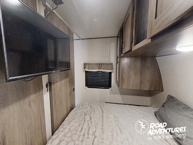 RV rental bedroom with a wall-mounted TV, comfy bed, window, and overhead cabinets for a cozy stay.. Prime Time Avenger 24BHS 2021