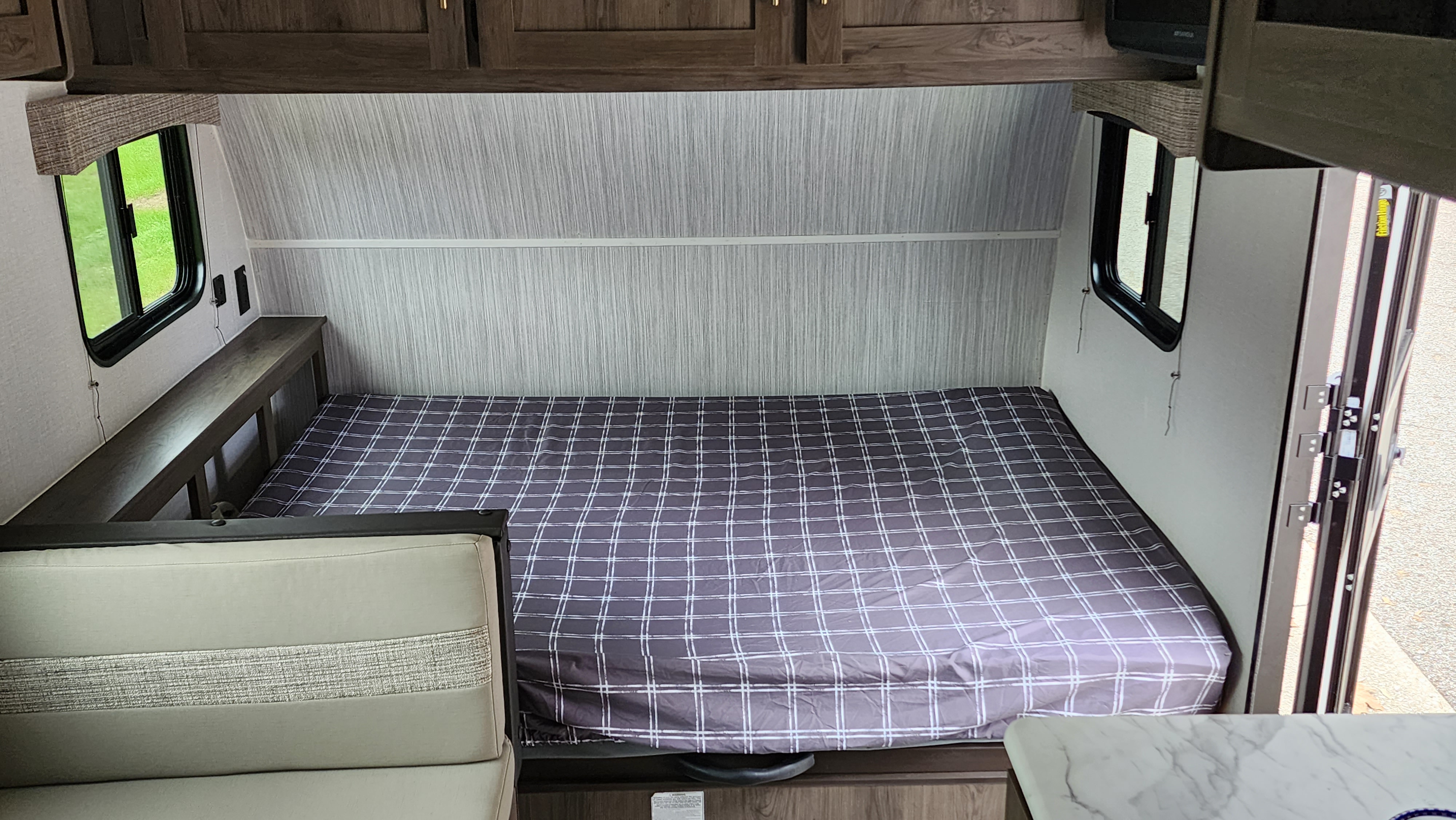 Cozy RV rental interior showcasing a large plaid bed, dinette, and windows, ideal for a comfortable camper setup.. Forest River Viking Ultra Lite 2022