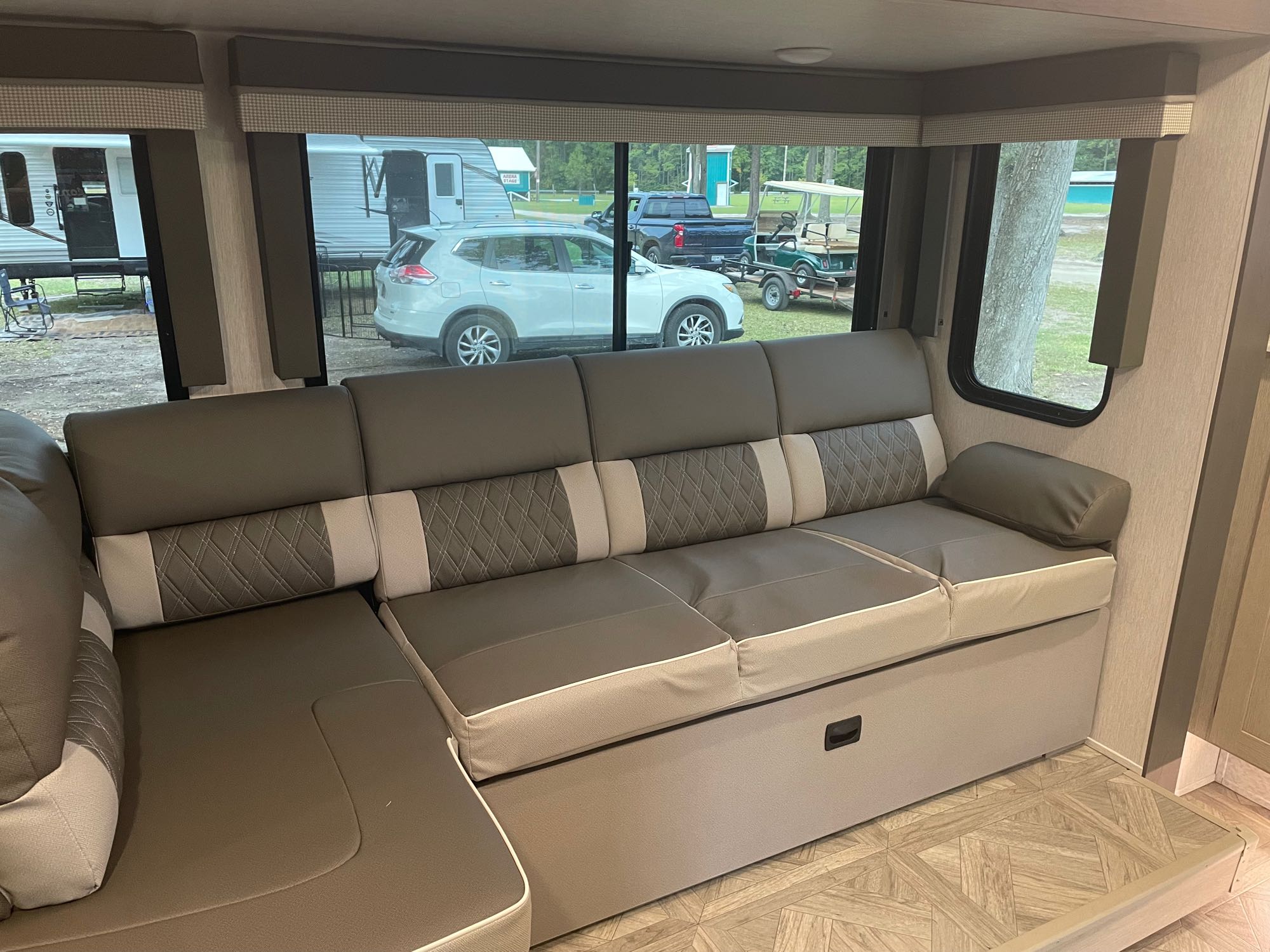 Comfortable RV rental interior with L-shaped seating, offering a view of the camper park outside. Ideal for your trip.. Forest River Wildwood X-Lite 2024