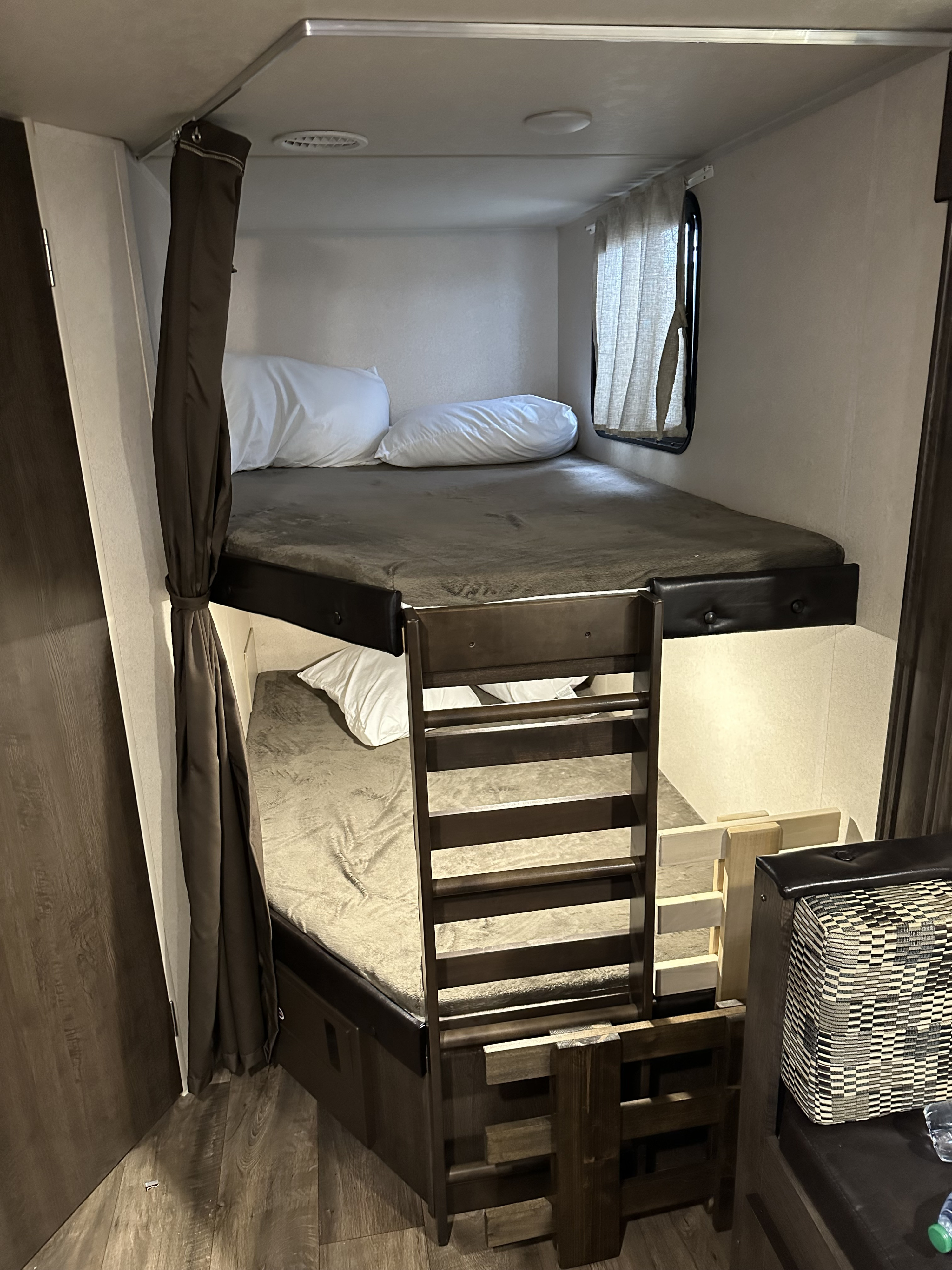 RV rental: Cozy bunk beds with a wooden ladder & privacy curtain inside a travel trailer, ready for guests.. Forest River Wildwood X-Lite 2018