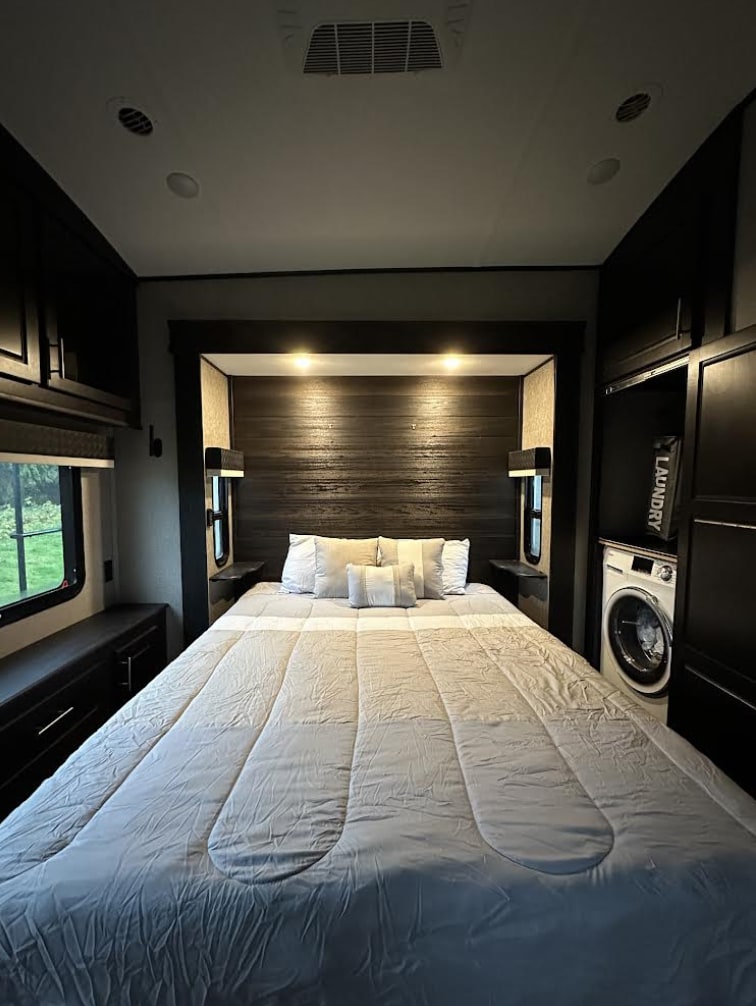 Spacious RV rental bedroom with a large bed, built-in storage, and a washer for convenient laundry.. Jayco North Point 2020