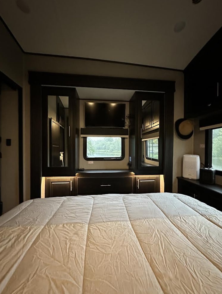 Spacious RV rental bedroom featuring a large bed, built-in TV, and mirrored storage, ideal for comfortable travel.. Jayco North Point 2020
