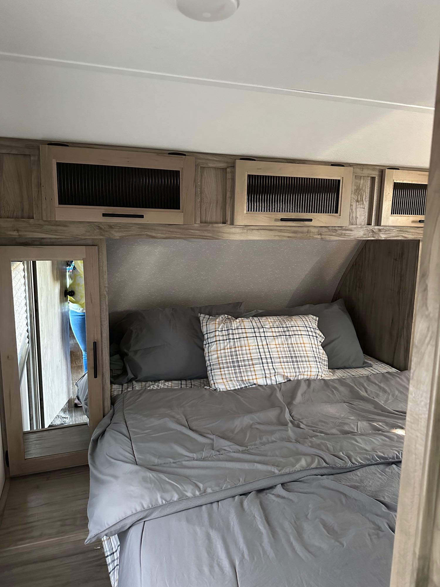 Experience comfort in this RV rental bedroom featuring a bed with grey bedding, overhead storage, and a mirror.. Forest River Cherokee Alpha Wolf 2021