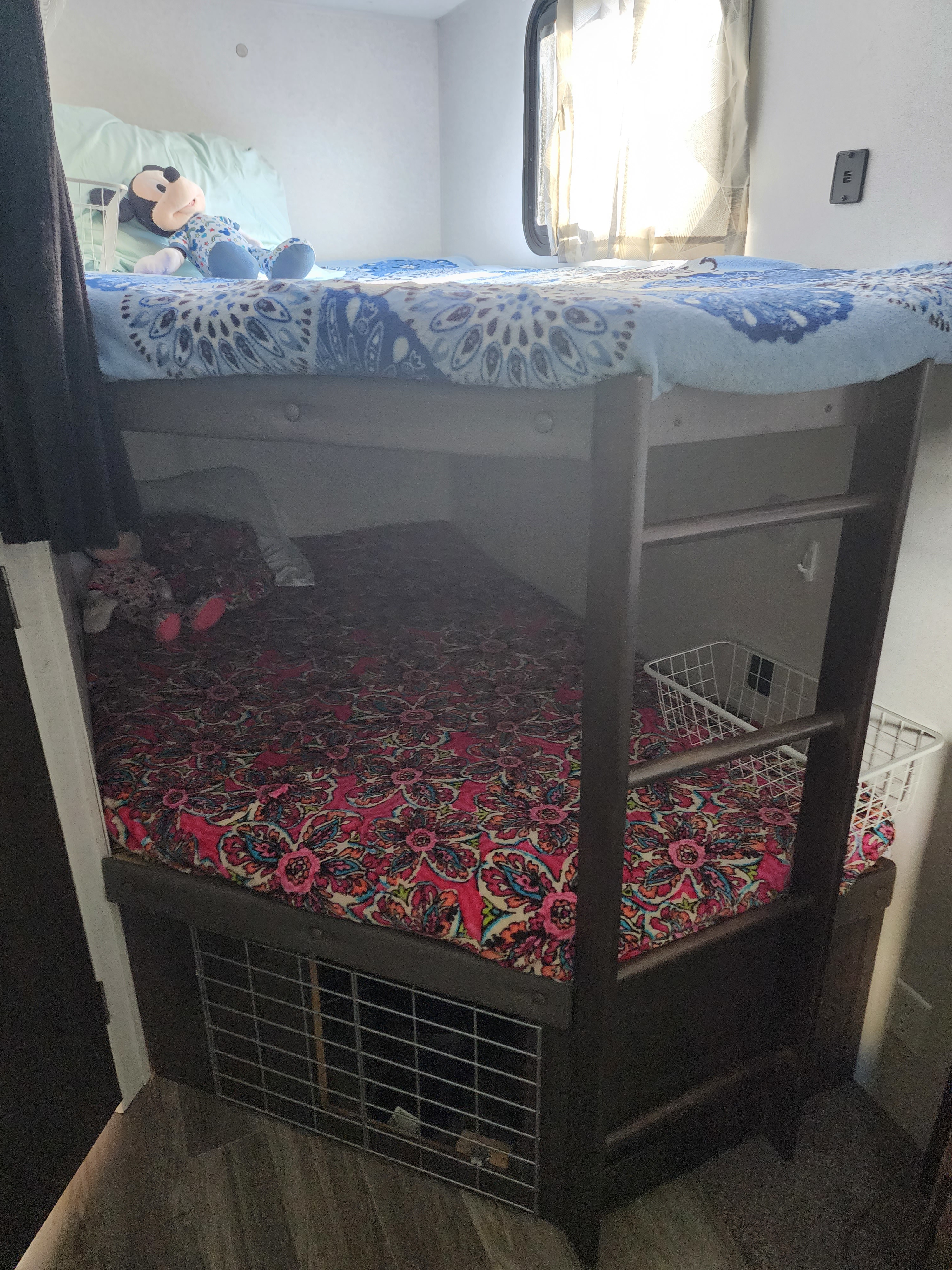 Cozy bunk beds in an RV rental, featuring colorful blankets, plushies, and under-bed storage for travel adventures.. Forest River Wildwood 2019