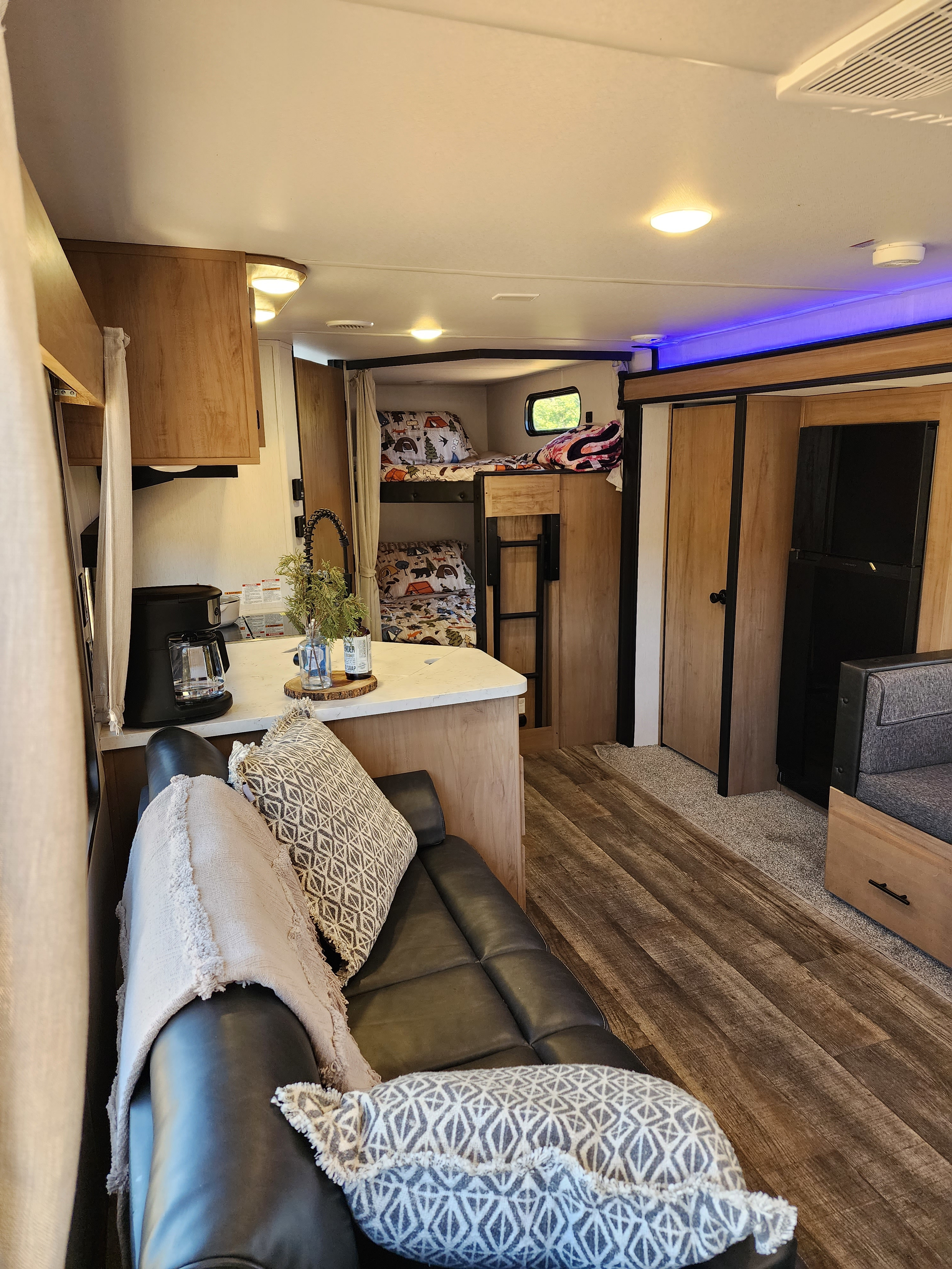Inside a spacious RV rental: a kitchen, bunk beds, and cozy lounge area. Enjoy compact living on your next travel adventure.. Forest River Cherokee 2023