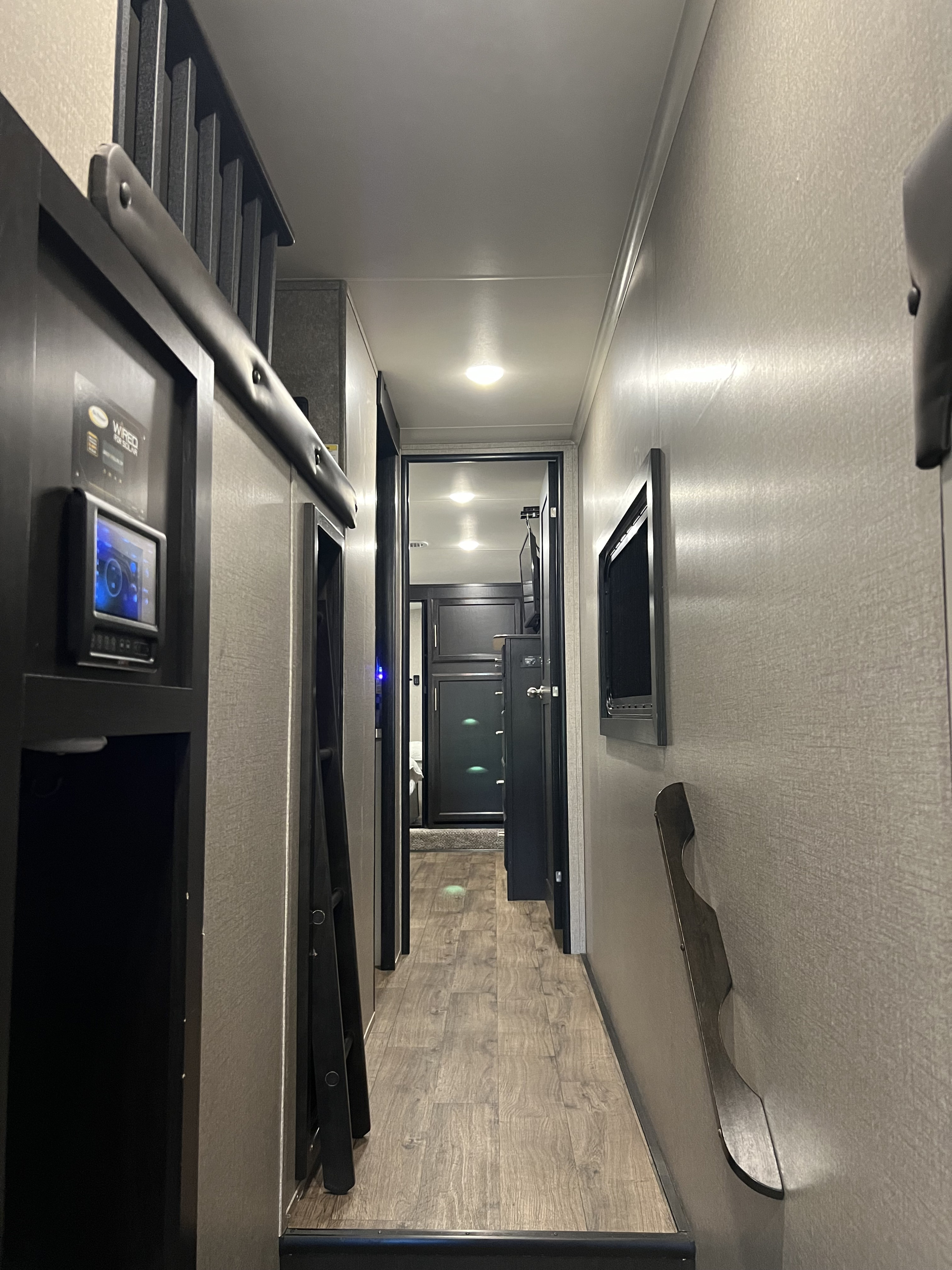 RV rental interior hallway with a control panel, bunk ladder, and wall-mounted TV.. Jayco Eagle 2021