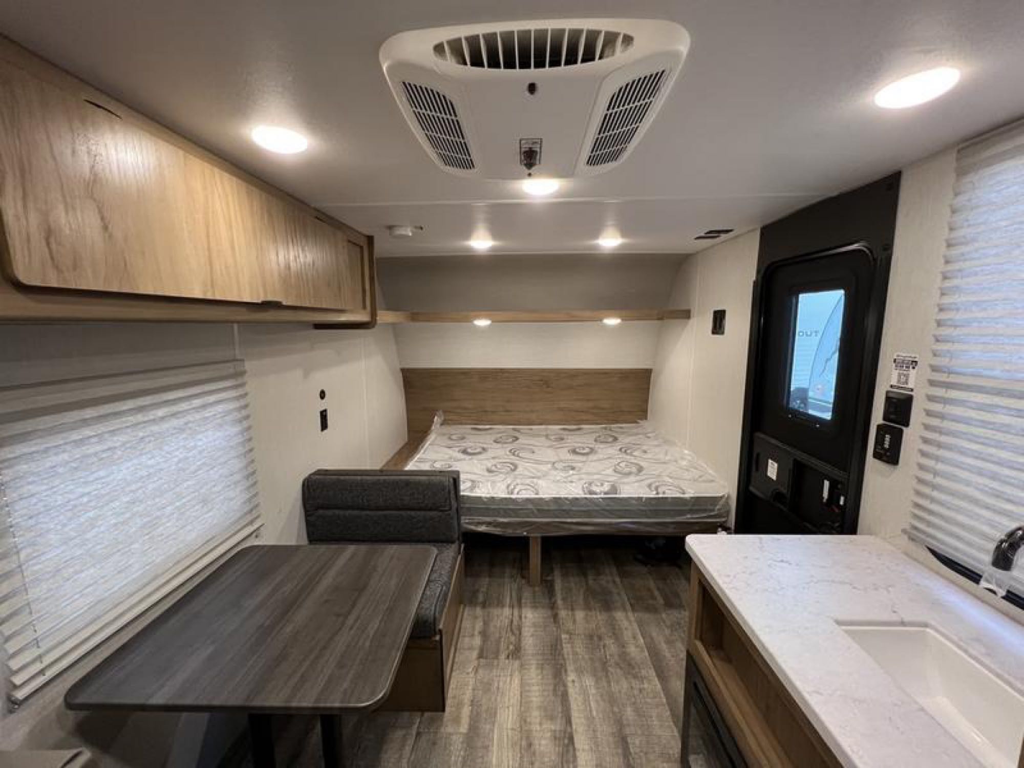 Bright RV rental interior: cozy bed, dinette, kitchen, and AC unit of this travel trailer shown.. Forest River Cherokee Wolf Den 16EV 2024