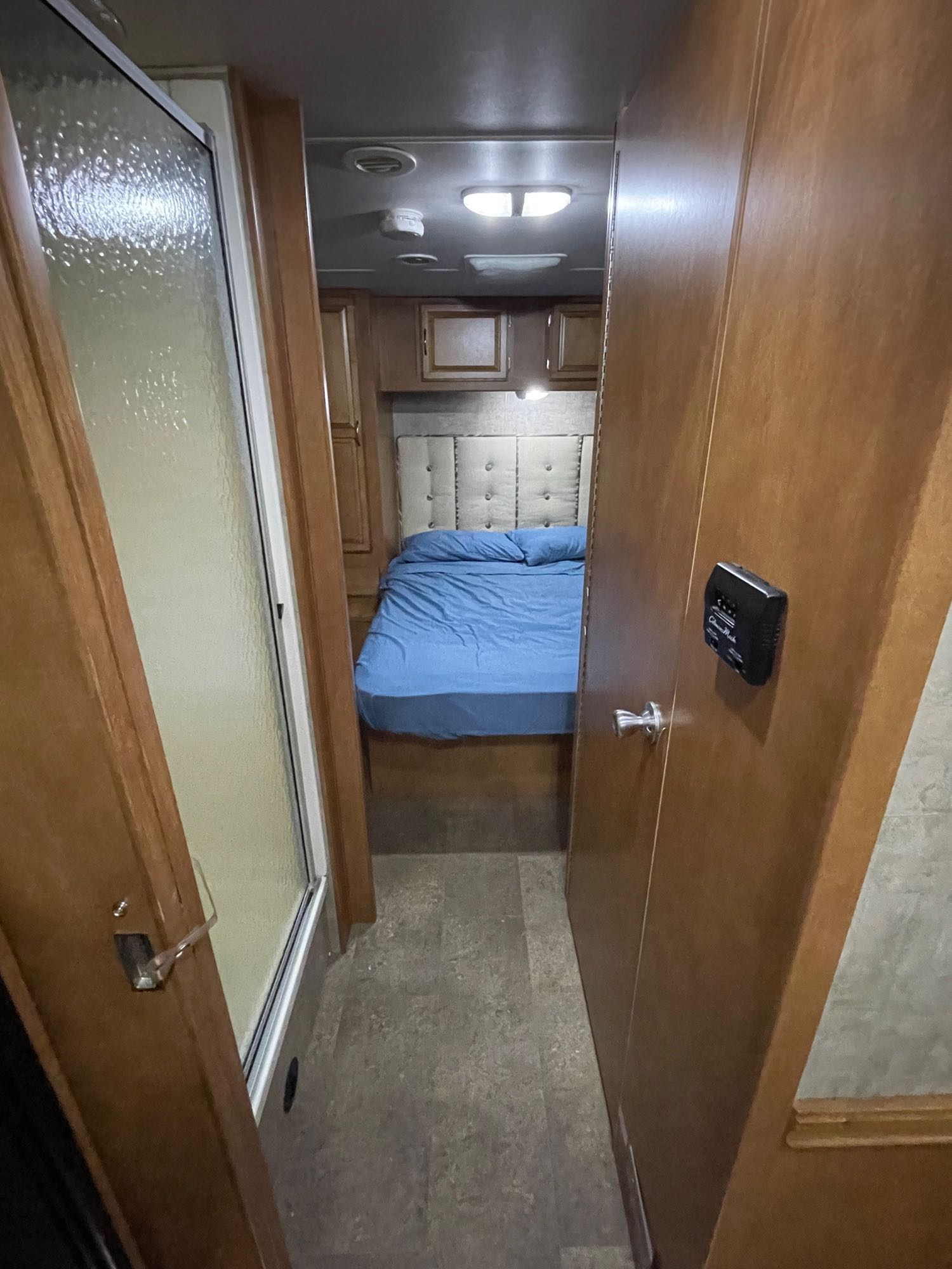 Step inside this cozy RV rental, featuring a compact bedroom with a blue bed and a shower stall, perfect for mobile adventures.. Winnebago Minnie Winnie 2016