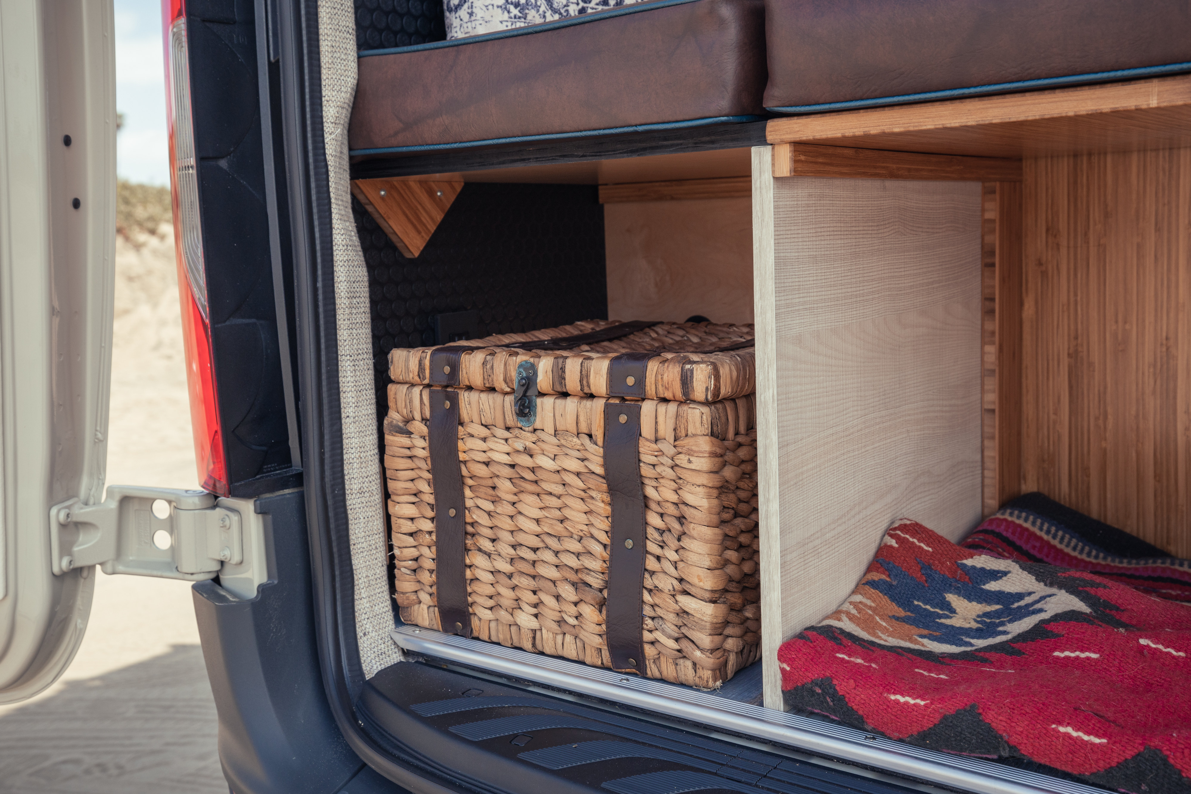 This RV rental's organized interior features custom storage: a woven trunk & colorful blanket, ready for your adventures.. Mercedes-Benz Sprinter 2022