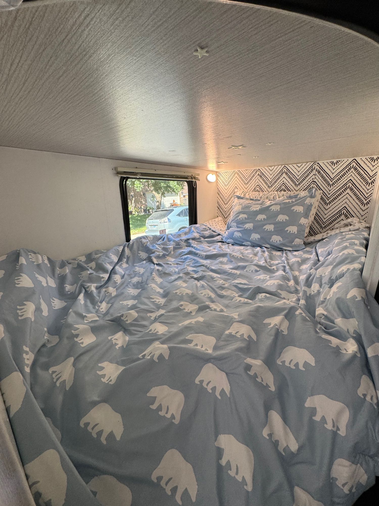 RV rental bedroom view: a cozy bed with blue polar bear bedding and a patterned headboard.. Heartland RVs Trail Runner 2020