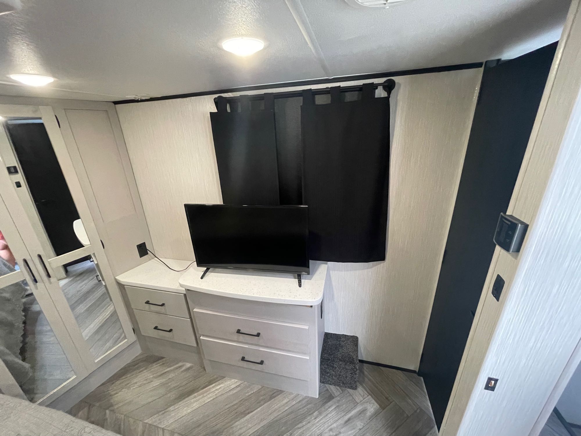 Spacious RV rental bedroom with TV, dresser, dark window curtains, and reflective closet doors. Ideal for travel comfort.. Heartland Cyclone 2022