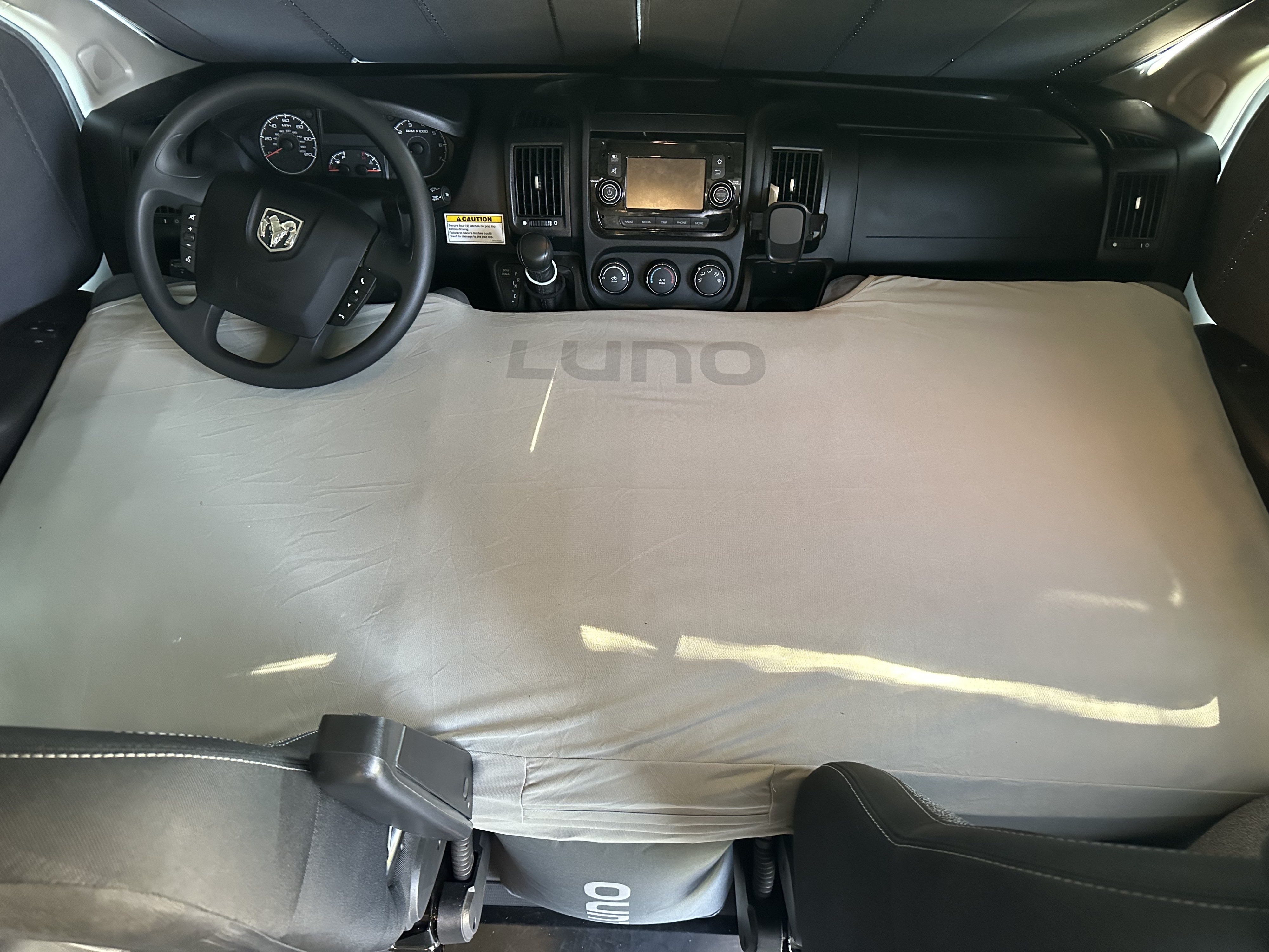 RV rental front cabin transformed into a sleeping area with a LUNO mattress covering the floor and dashboard.. Winnebago Solis 2022