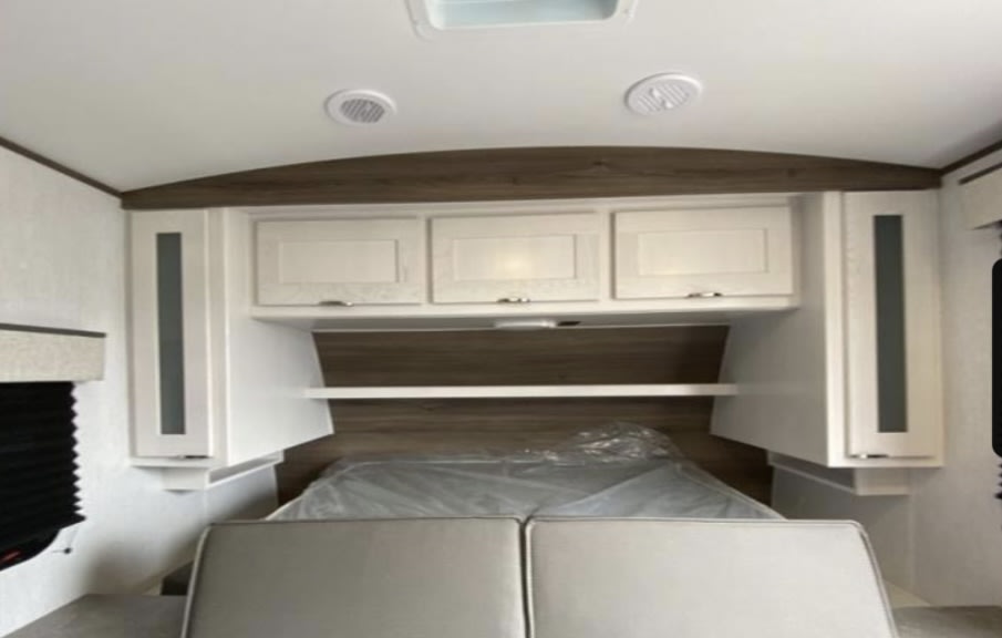 RV rental interior: cozy bedroom with bed, overhead cabinets, and side storage.. Cruiser RV MPG 2023