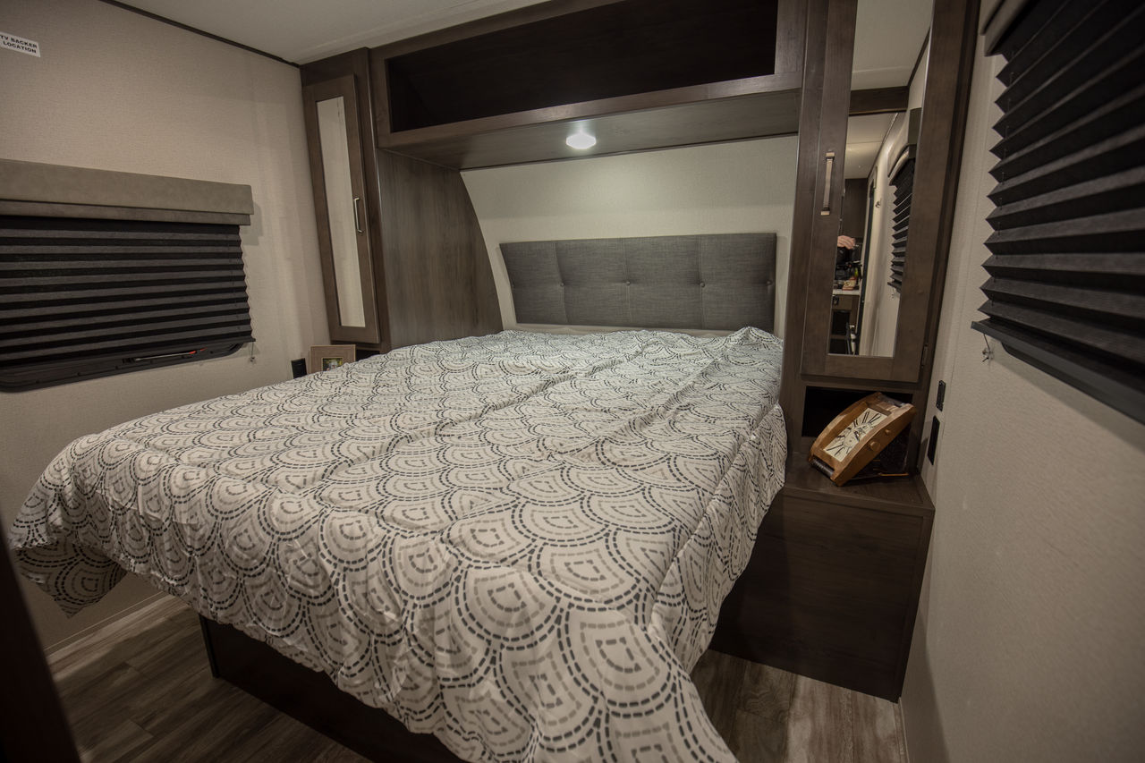 Cozy RV rental bedroom with patterned bedding, built-in storage, and window blinds, offering comfort for your travels.. Grand Design Transcend Xplor 2021