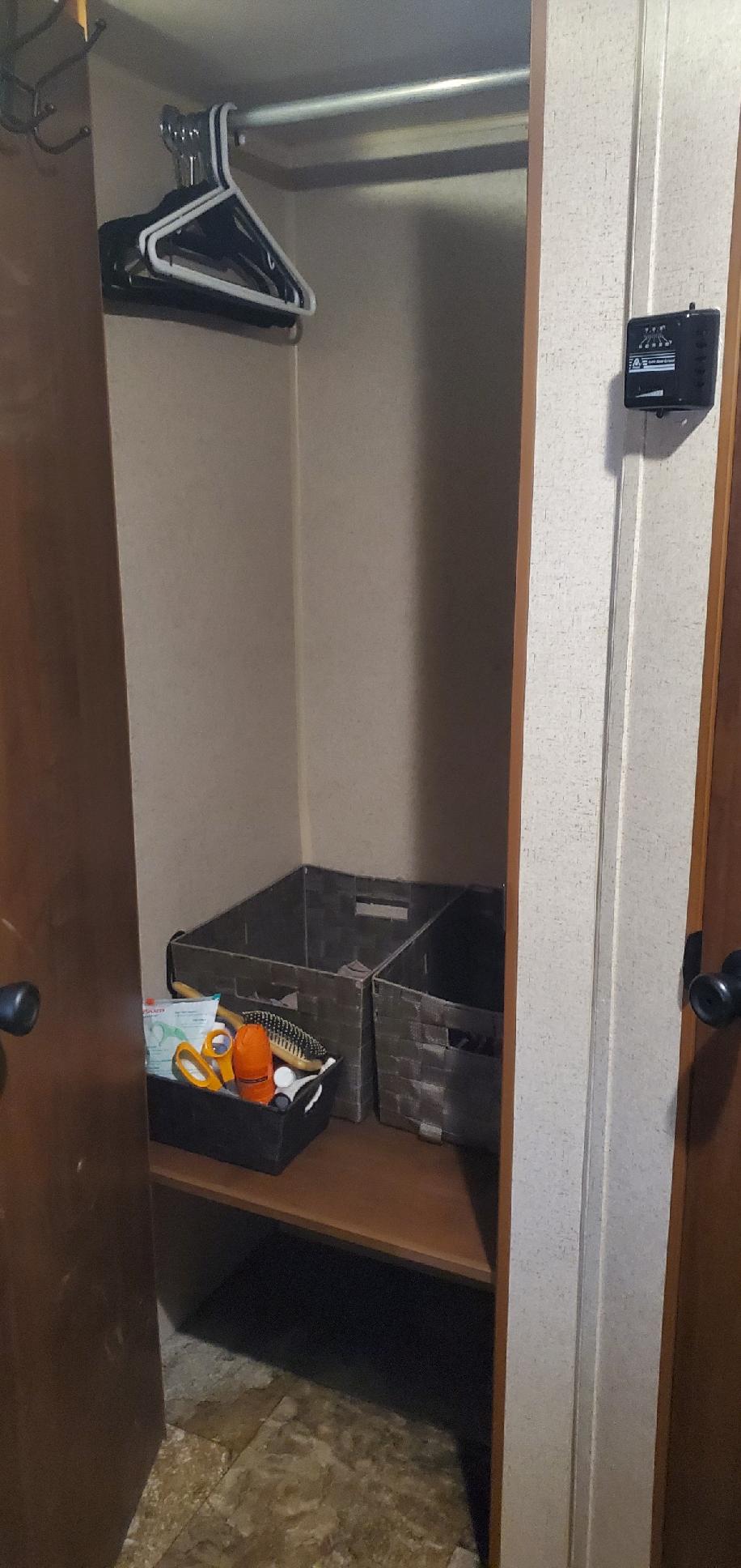 Organized RV rental closet featuring a hanging rod, hangers, and storage bins, with a control panel on the exterior wall.. Jayco Jay Flight Swift SLX 2014