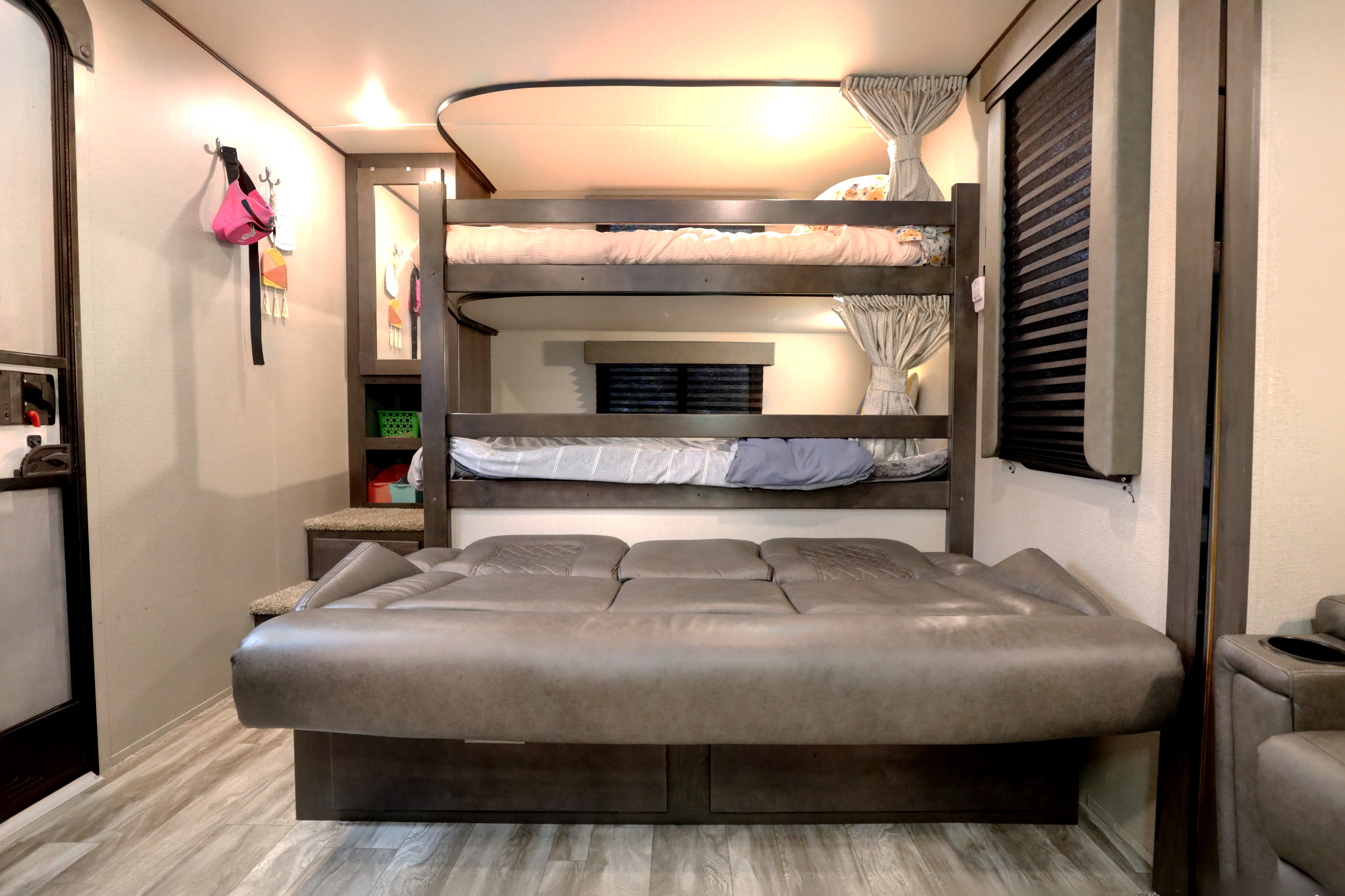 Versatile RV rental interior: bunk beds over a fold-down sofa bed, plus storage and a window.. Grand Design Transcend Xplor 2022