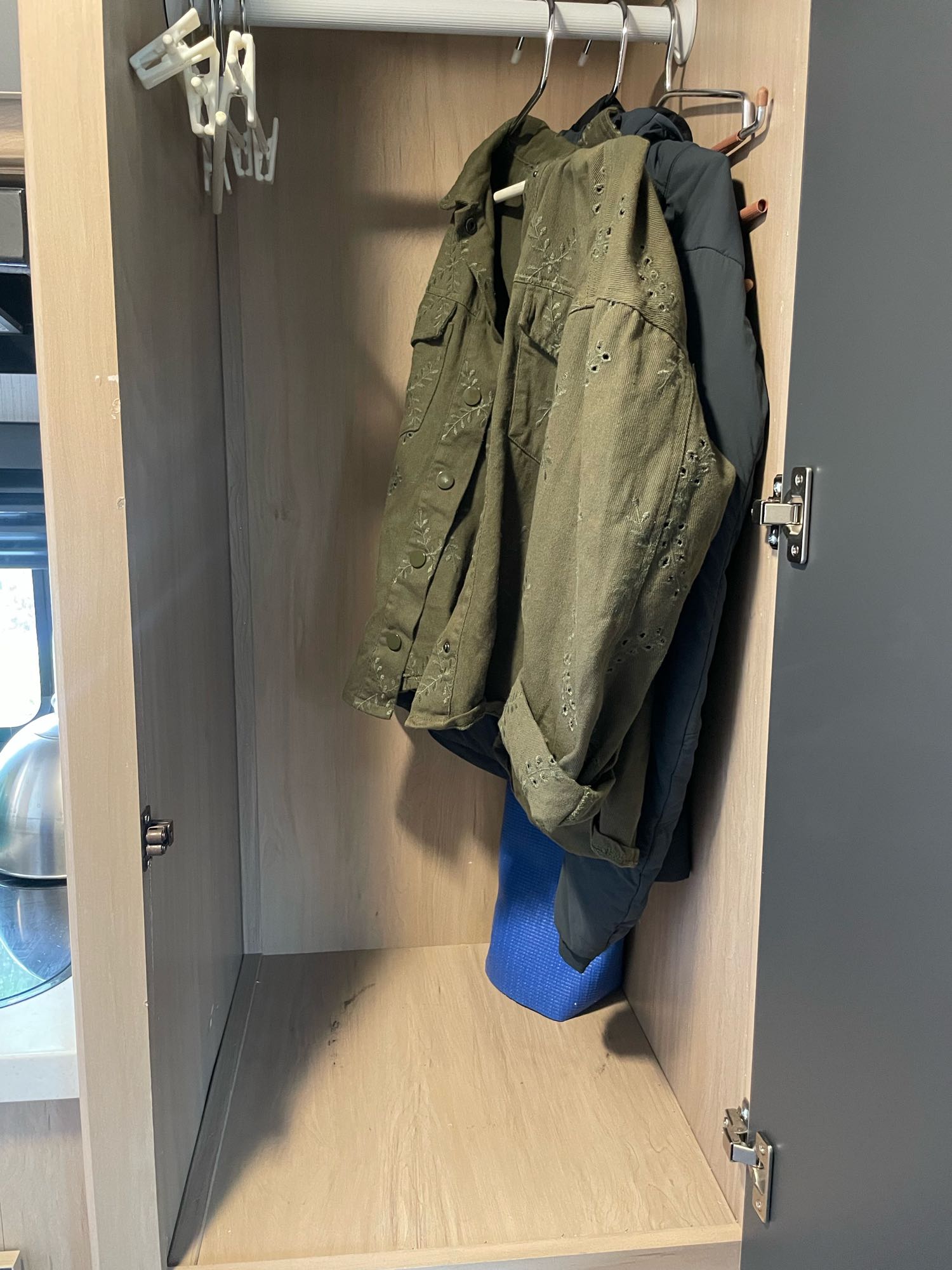 Inside a compact RV rental closet: two jackets hang, with clothes hangers & a blue mat below, ideal for storage.. Cruiser RV Hitch 16RD 2022